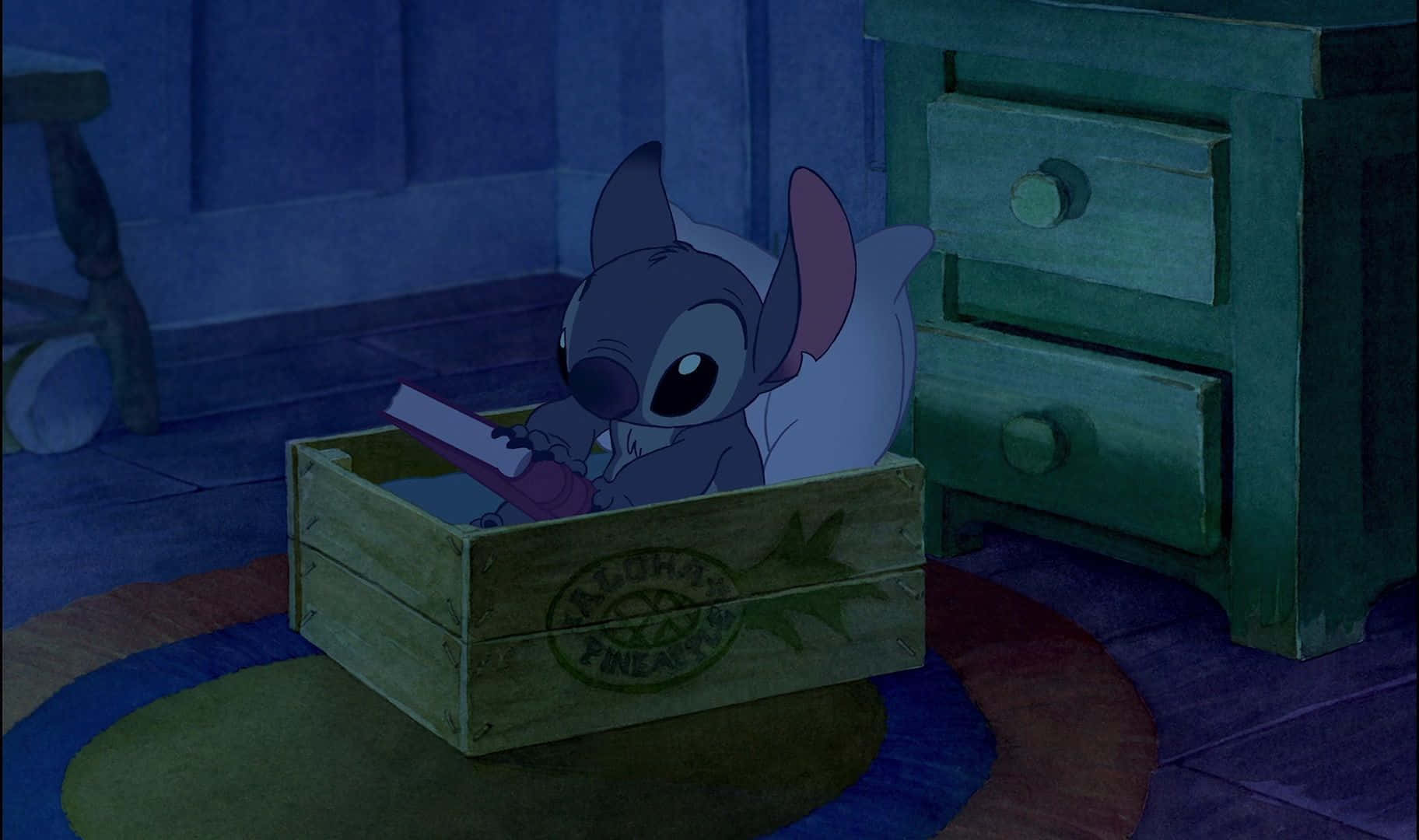 Cute Lilo And Stitch 桌布 壁紙 — 一個藍色小外星人，大眼睛，坐在木箱裡，在燈光昏暗、有青綠色家具的房間裡看書。