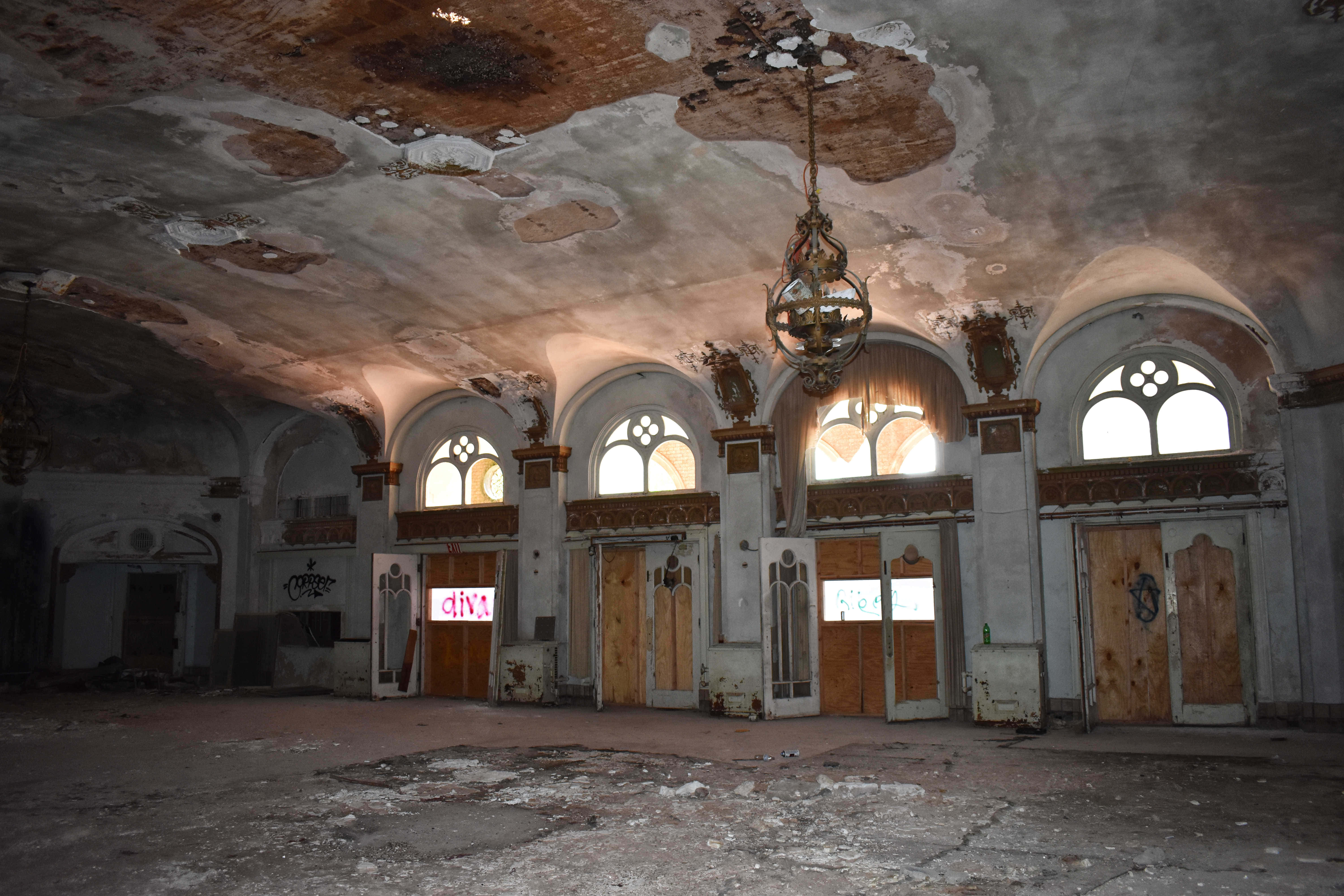Haunted Hotels 桌布 壁紙 — 一個被遺棄的大廳，天花板剝落，拱形窗戶讓柔和光線透入。