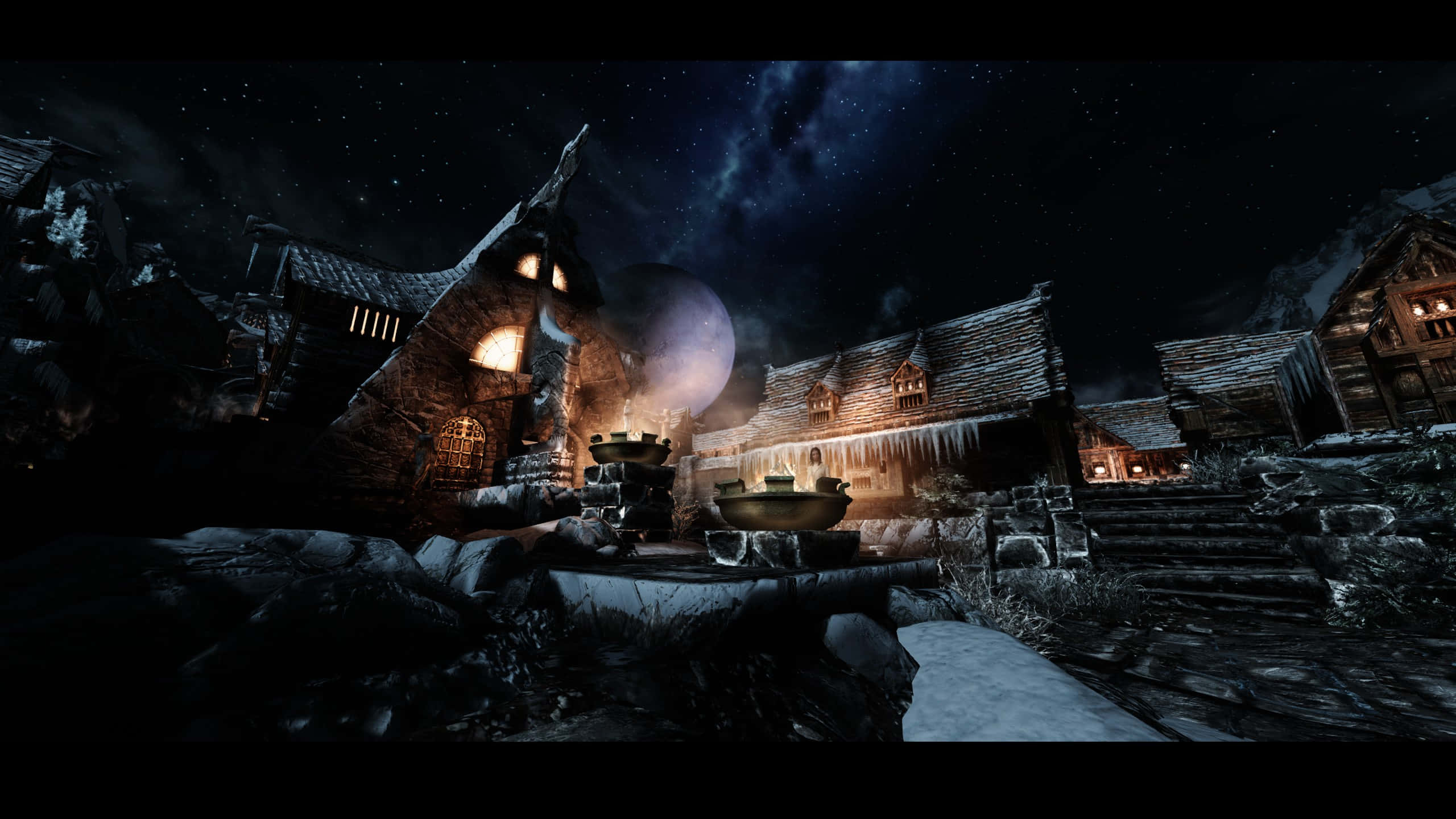 Skyrim Windhelm 桌布 壁紙 — 一個被雪覆蓋的中世紀村莊夜晚，窗戶發光，星空中有大月亮。