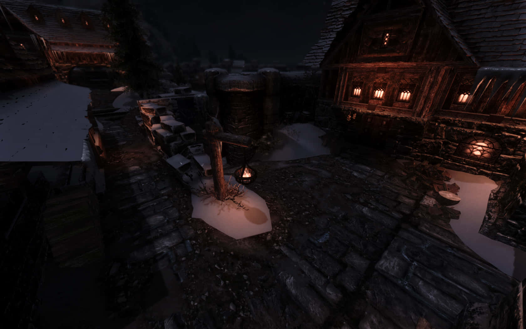Skyrim Windhelm 桌布 壁紙 — 一個被雪覆蓋的中世紀村莊夜景，木屋中透出溫暖的燈籠光芒，中央的篝火照亮了積雪。