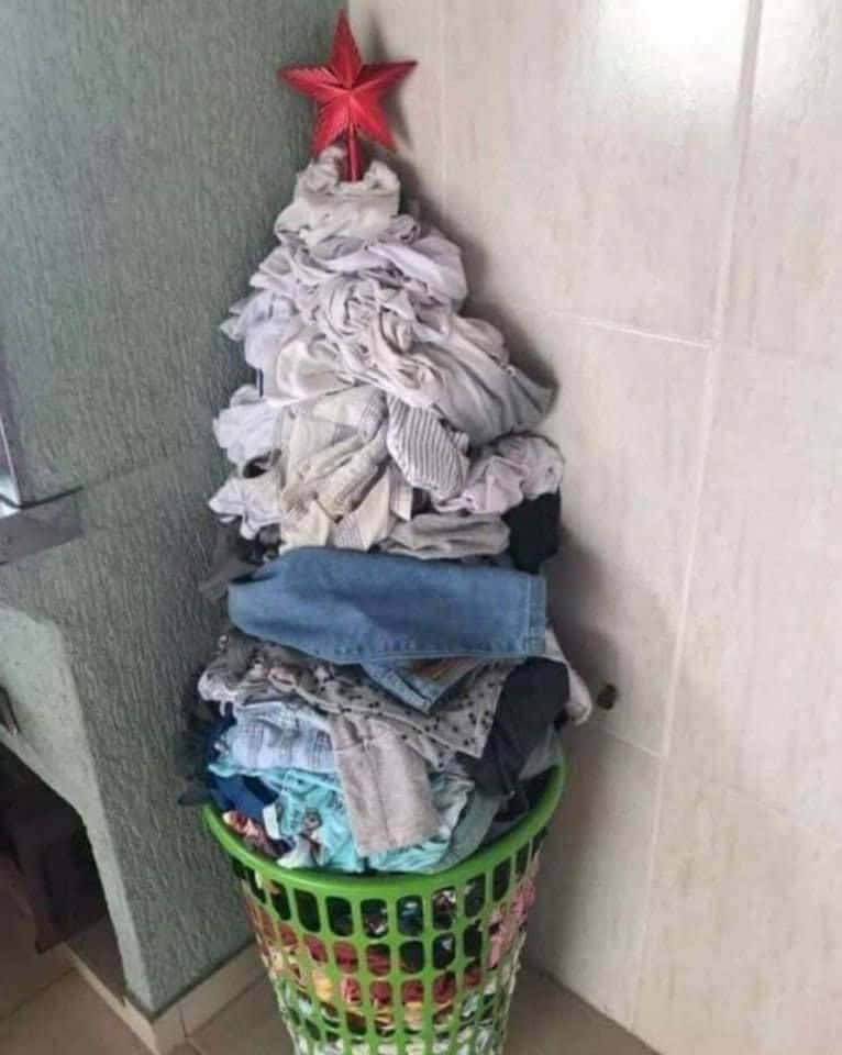 Holiday Memes 桌布 壁紙 — 一個裝滿衣物、堆成聖誕樹形狀並頂著一顆紅星的洗衣籃。