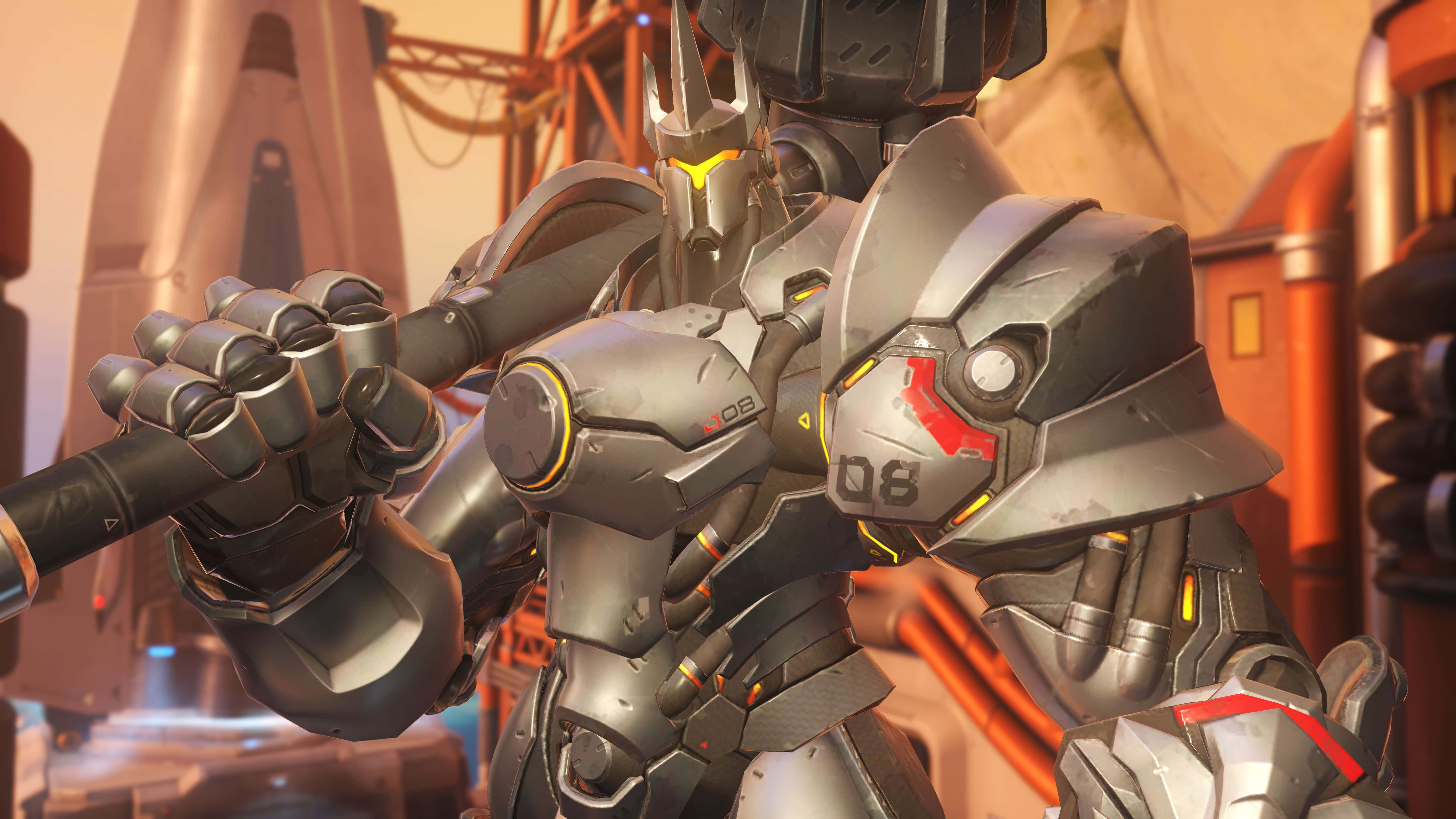 Overwatch Reinhardt 桌布 壁紙 — 一個裝甲厚重的機械戰士，帶有發光的黃色點綴，在未來工業環境中握著武器。