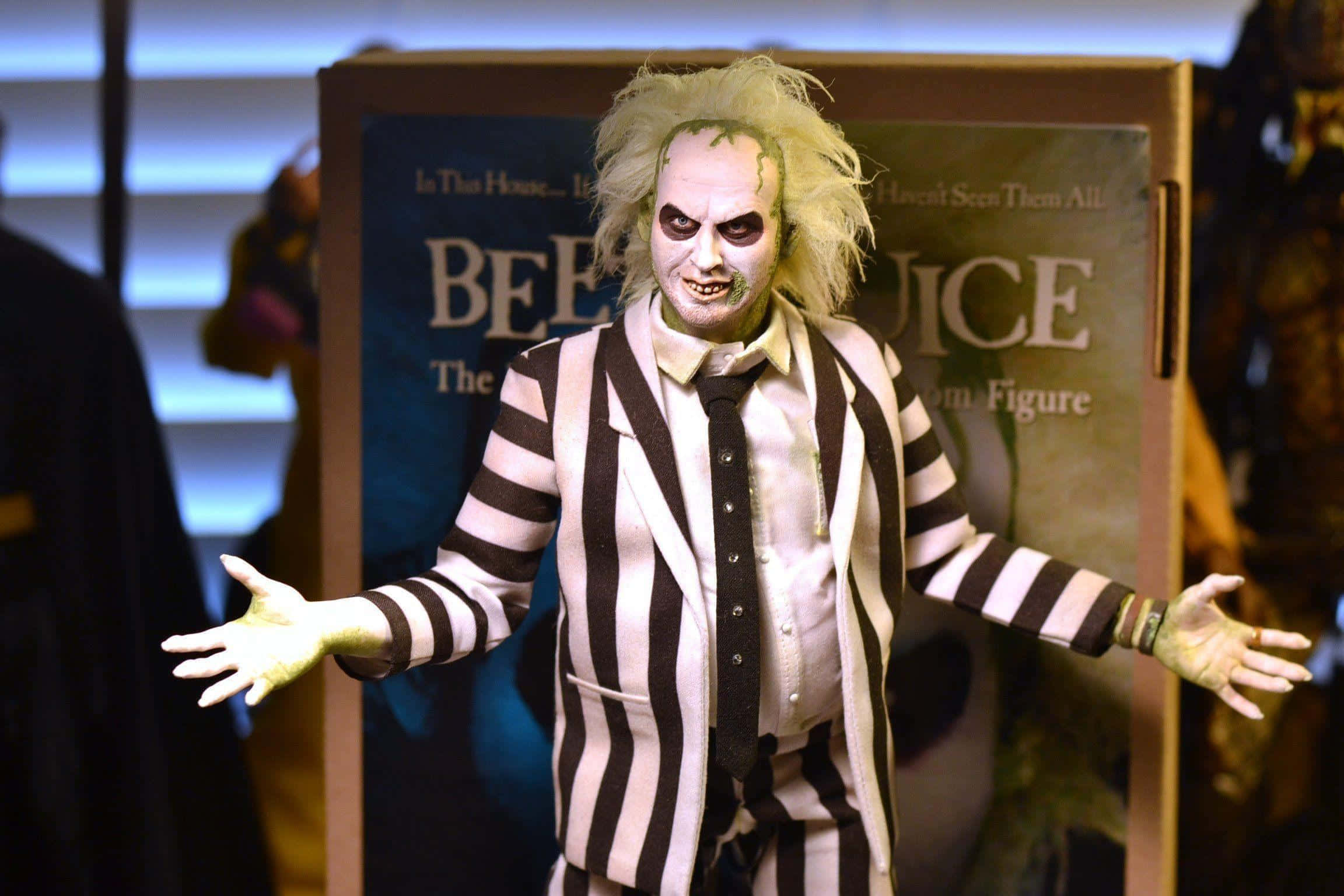 Beetlejuice 桌布 壁紙 — 一個詳細的Beetlejuice動作人偶站在宣傳背景前，雙臂伸展。