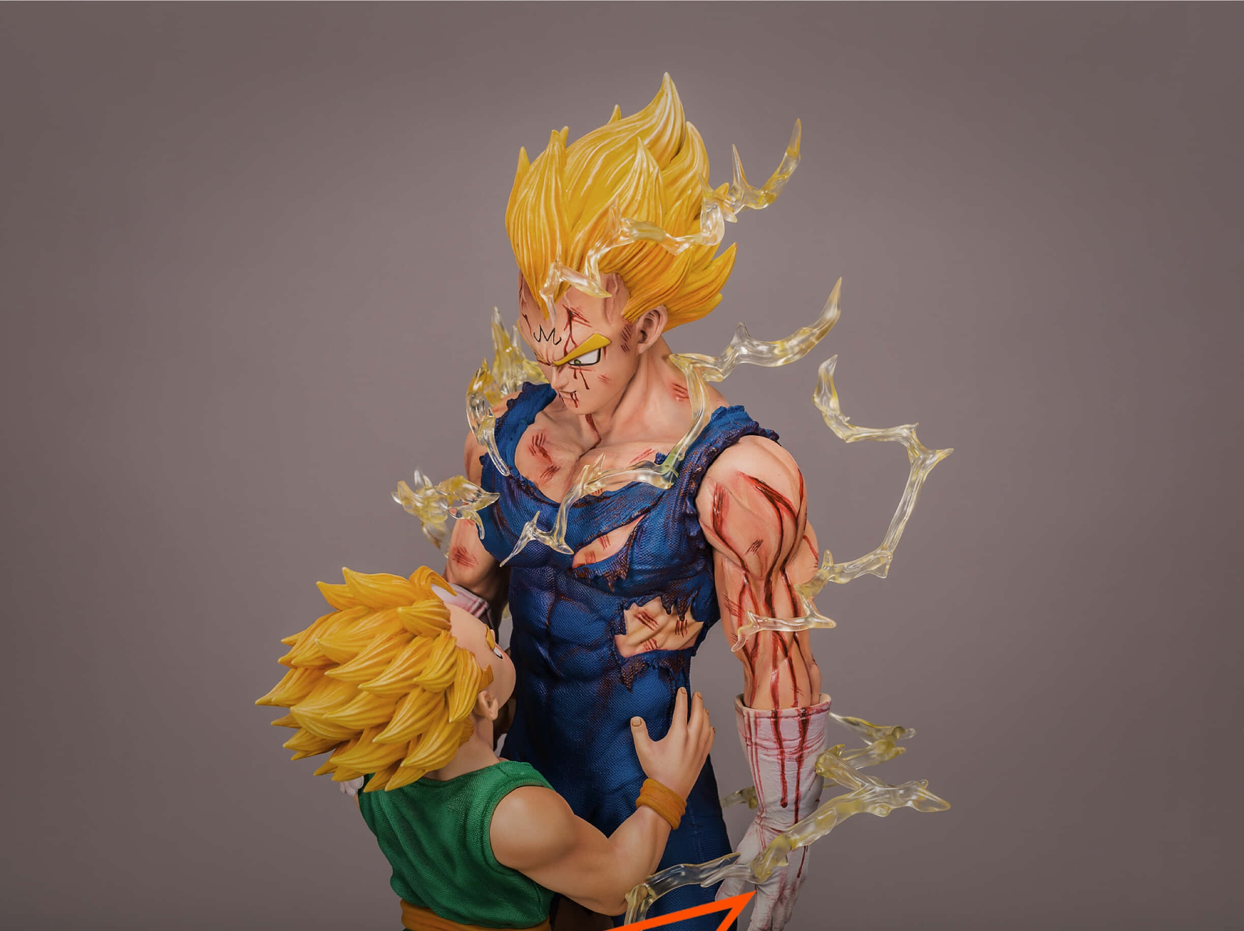 Vegeta And Trunks 桌布 壁紙 — 一個詳細的動漫人偶，描繪一位肌肉發達、金髮、帶有發光光環和傷痕的戰士，抱著一個穿著綠色襯衫的小孩。