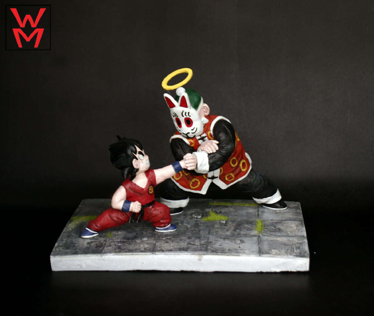 Grandpa Gohan 桌布 壁紙 — 一個詳細的模型，描繪一個穿著紅色衣服的小孩在黑暗背景下的石質底座上與一個戴著面具、帶有光環的天使般的人物戰鬥。