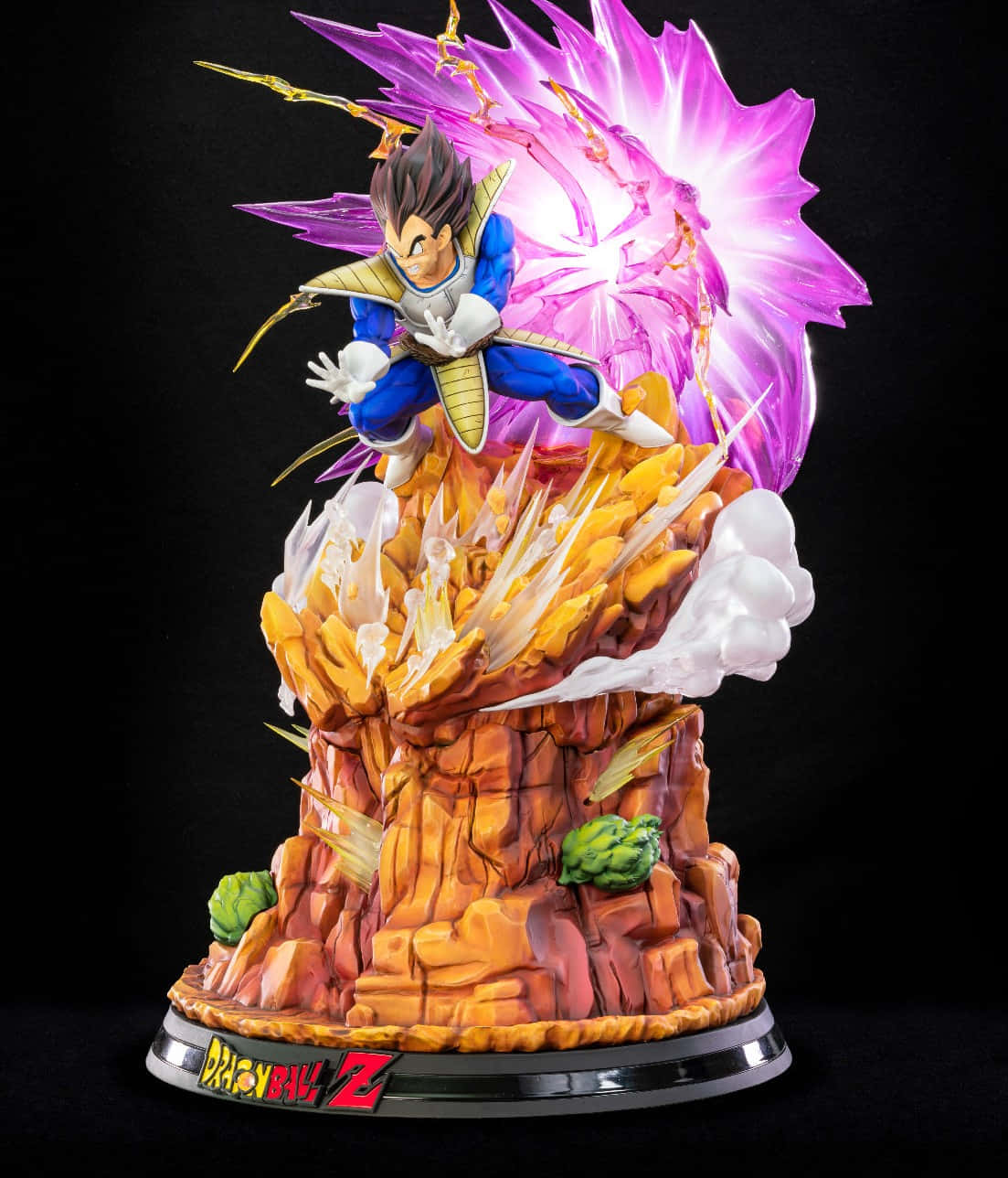 Vegeta Galick Gun 桌布 壁紙 — 一個詳細的比達超級撒亞人形態雕像，在帶有龍珠Z標誌的岩石底座上釋放紫色能量爆炸。