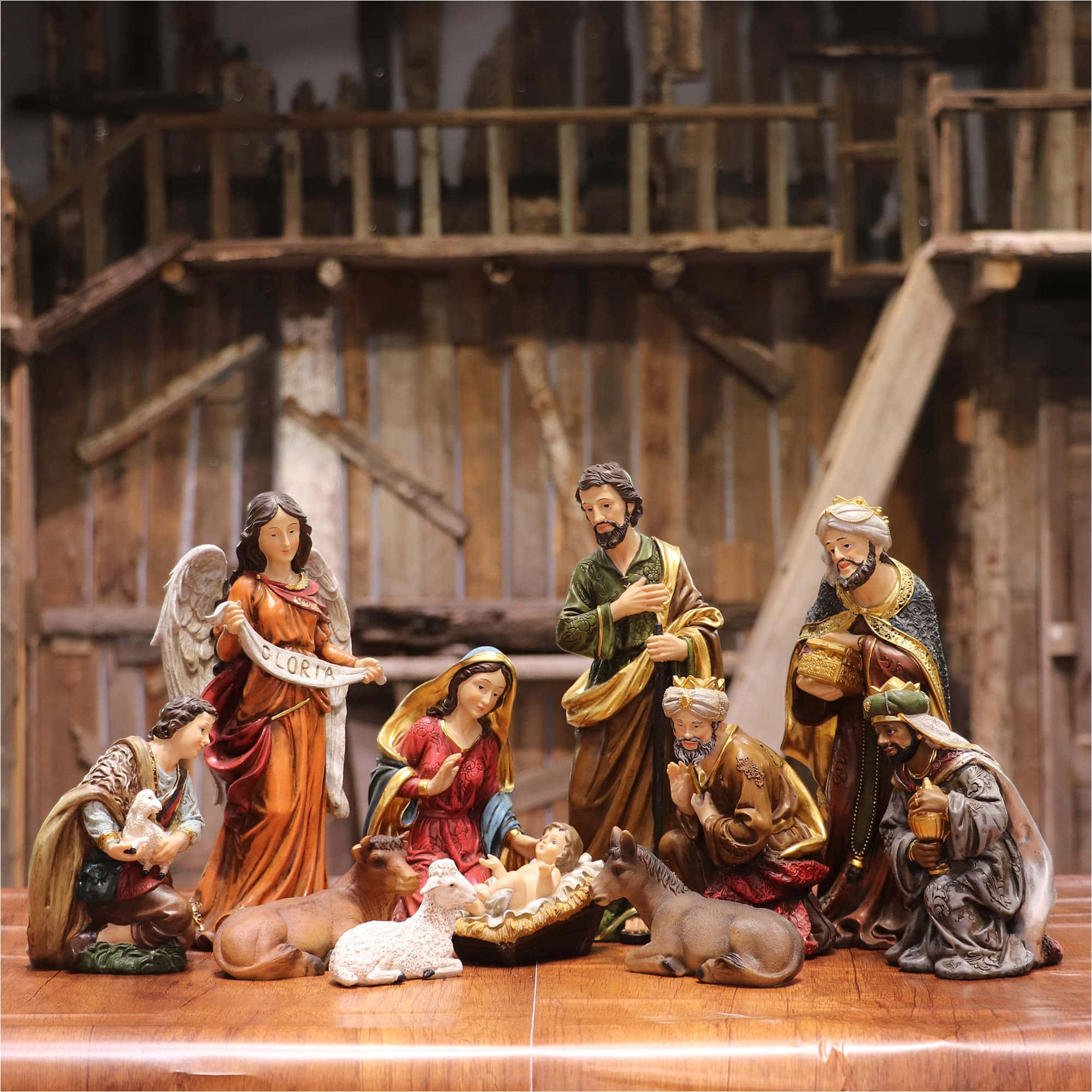 Nativity Scene 桌布 壁紙 — 一個詳細的耶穌誕生場景公仔套裝，包括瑪利亞、約瑟、嬰兒耶穌、牧羊人、智者及一位天使，聚集在木質表面上的馬槽周圍。