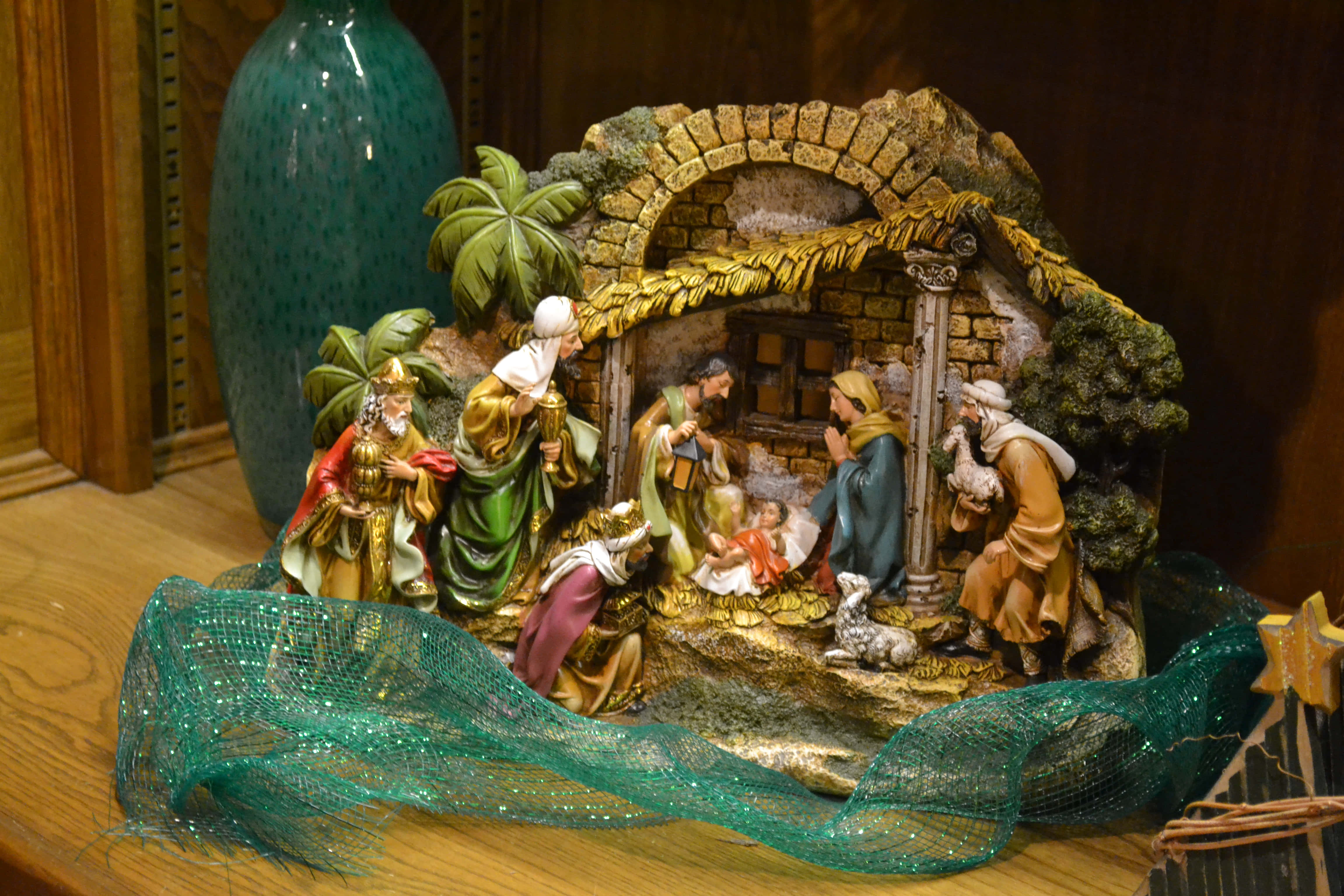 Nativity 桌布 壁紙 — 一個詳細的耶穌誕生場景雕像，包含瑪利亞、約瑟、嬰兒耶穌、東方三博士和牧羊人，圍繞著木架上的石馬槽排列。