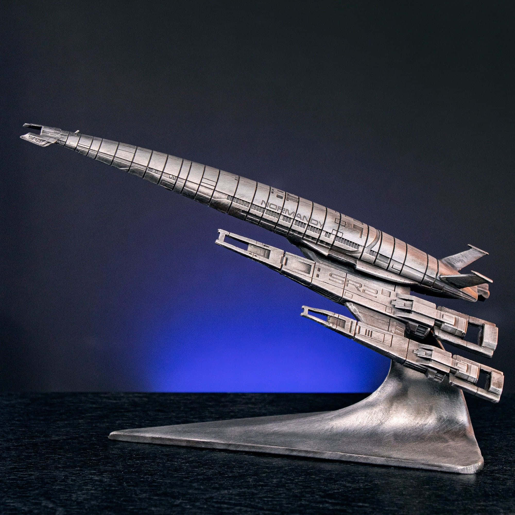 Normandy Sr-2 桌布 壁紙 — 一個詳細的金屬模型，展示諾曼第SR2太空船，放置在時尚的支架上，背景為深藍色漸變。