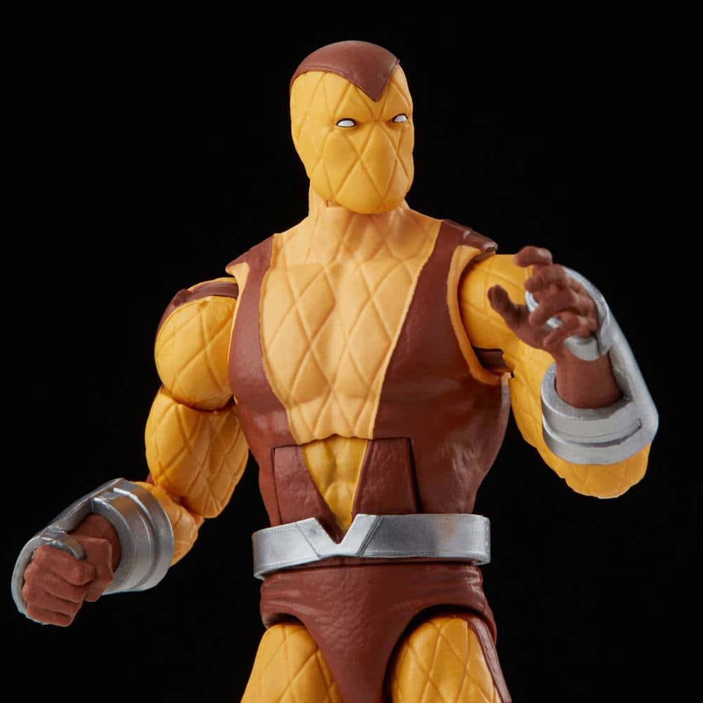 The Shocker 桌布 壁紙 — 一個詳細的黃色和棕色裝甲角色動作人偶，帶有銀色護腕，站在黑色背景前。