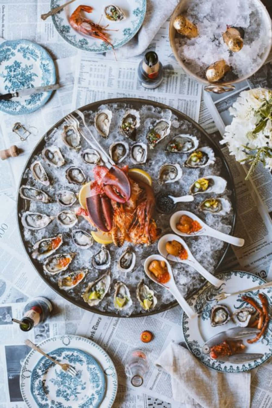Seafood 桌布 壁紙 — 一個豐盛的海鮮拼盤，以冰上的生蠔和鮮艷的龍蝦為主角，放在鋪滿報紙的桌子上。
