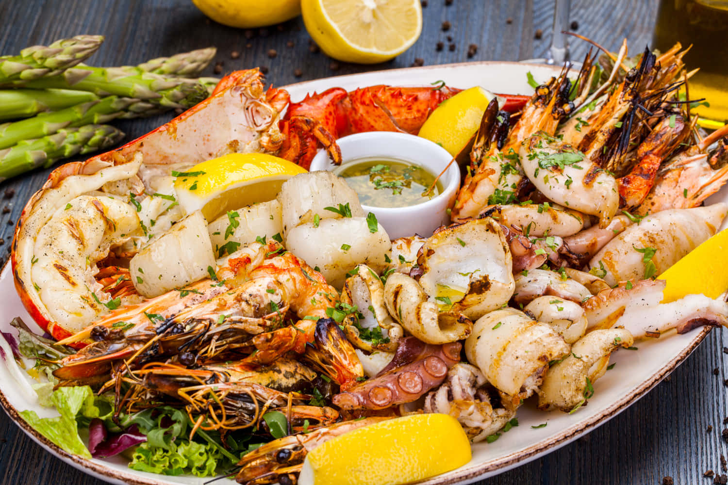 Seafood 桌布 壁紙 — 一個豐盛的烤海鮮拼盤，包括龍蝦、蝦和魷魚，用檸檬角和香草裝飾，放在質樸的木桌上。