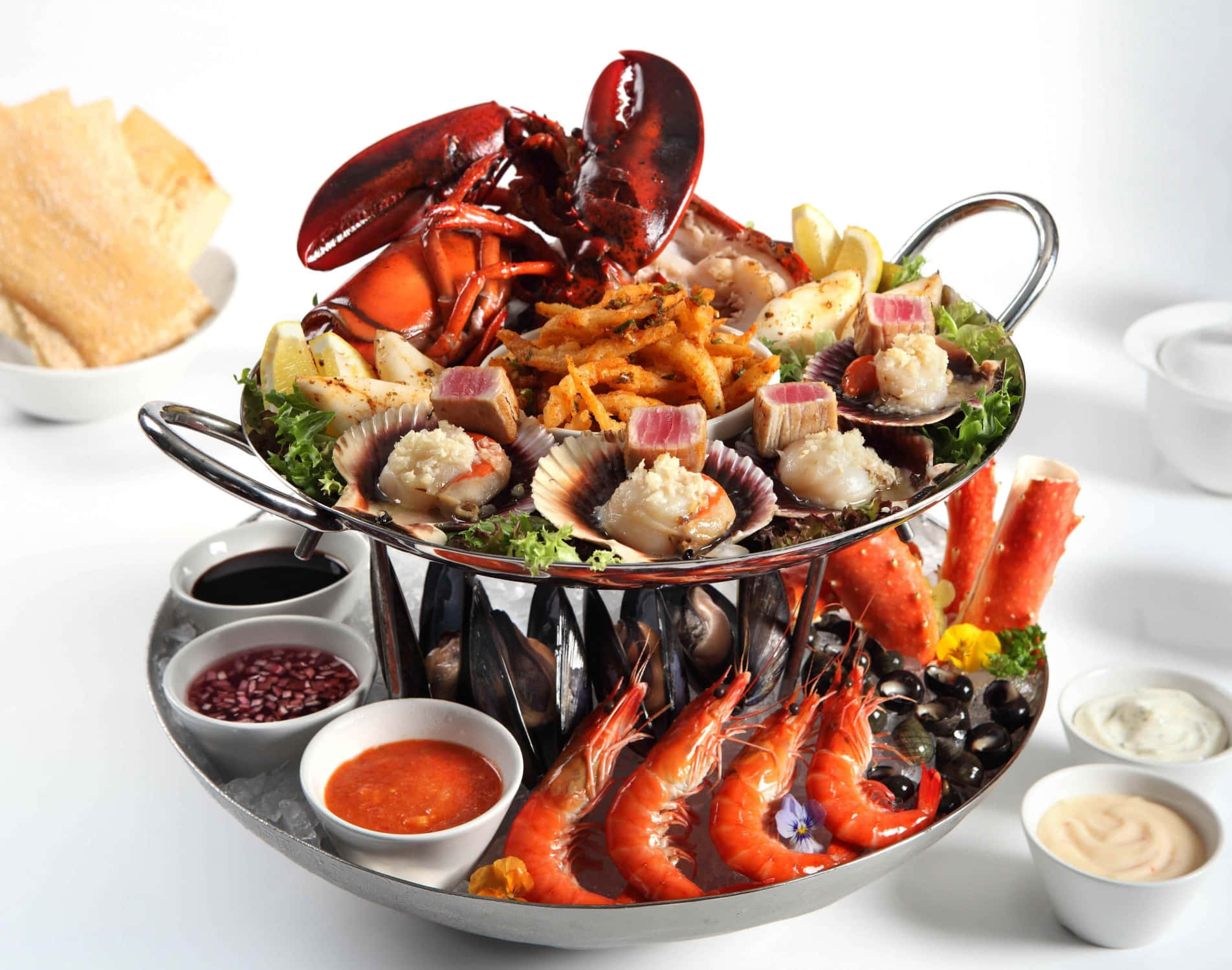 Seafood 桌布 壁紙 — 一個豪華海鮮拼盤，包括整隻龍蝦、扇貝、蝦、青口和蟹腳，擺放在兩層金屬架上，附有蘸醬。