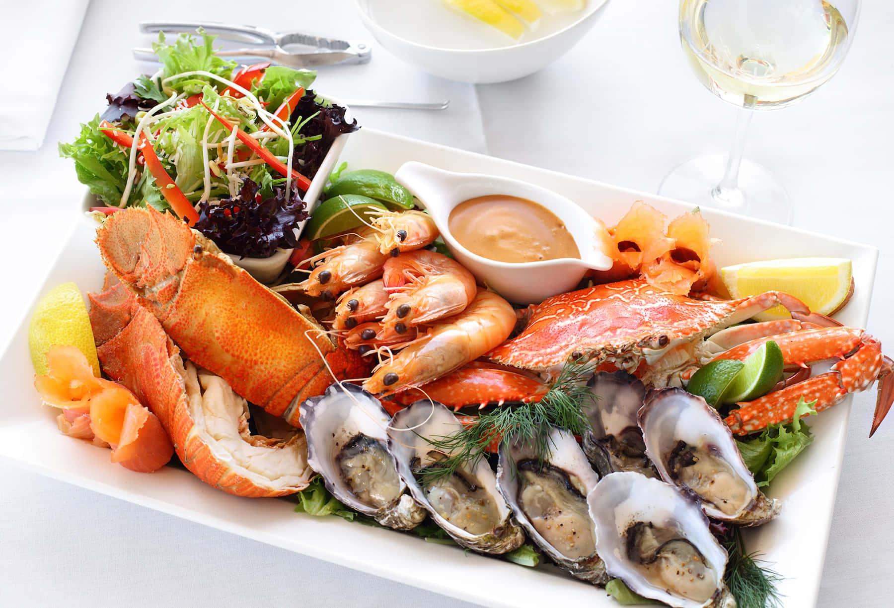 Seafood 桌布 壁紙 — 一個豪華海鮮拼盤，包括龍蝦、蟹、蝦和生蠔，配上檸檬和香草裝飾，放在白色碟上。