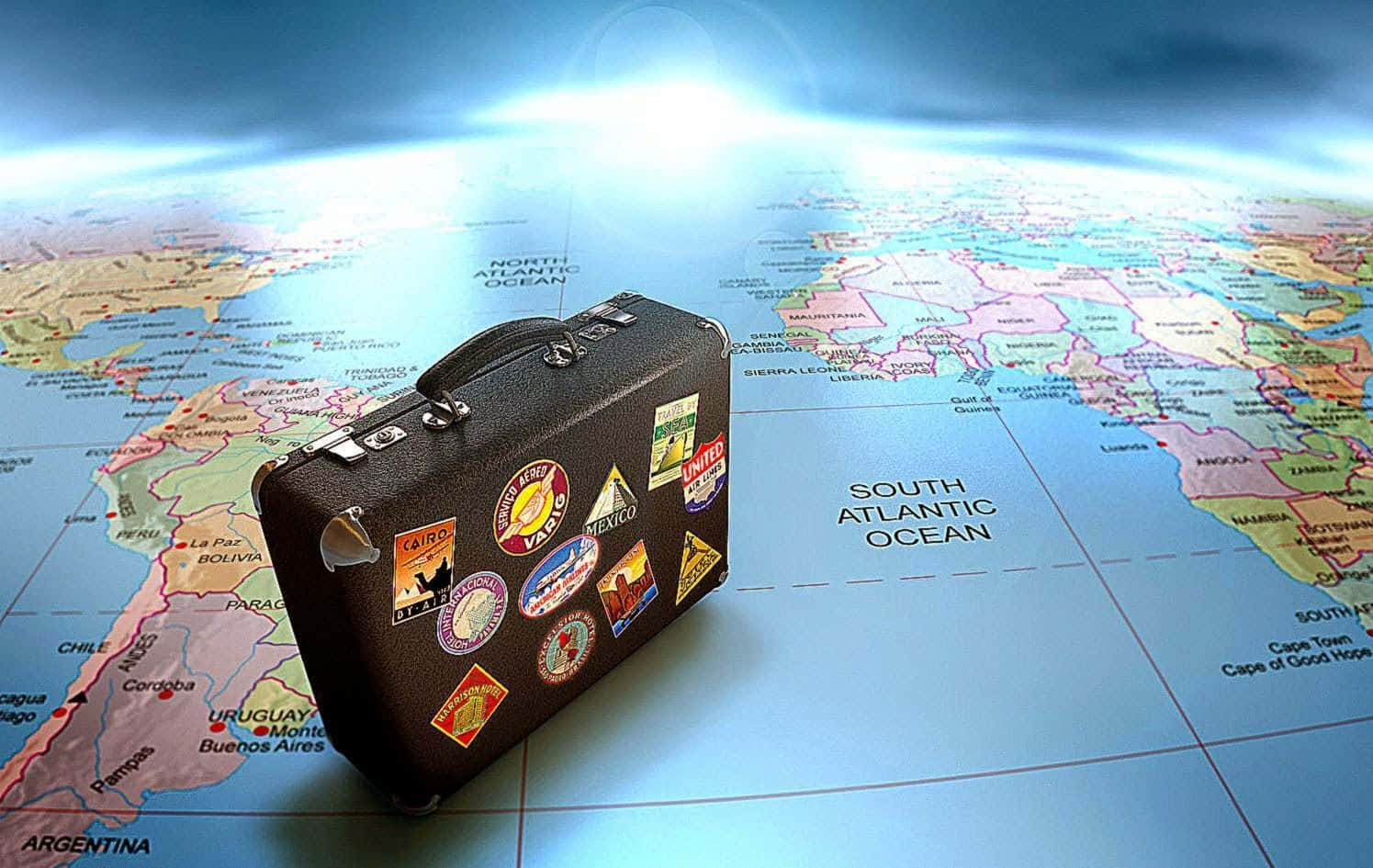 3d Travel 桌布 壁紙 — 一個貼滿旅行貼紙的復古行李箱放在一個帶有發光藍色地平線的世界地圖上。