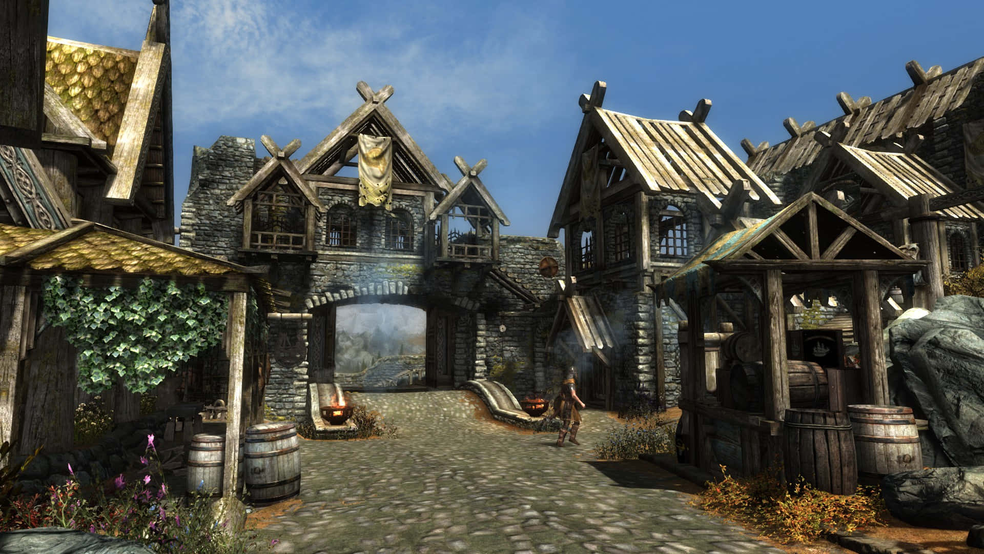Skyrim Whiterun 桌布 壁紙 — 一個質樸的中世紀村莊，有石頭和木頭建築、鵝卵石小徑，以及一個孤獨的身影走在木拱門下。