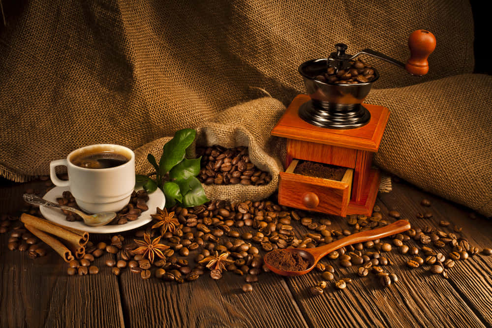 Brown Coffee 桌布 壁紙 — 一個質樸的咖啡靜物，白色杯子、肉桂棒和木製研磨機放在風化的木桌上。