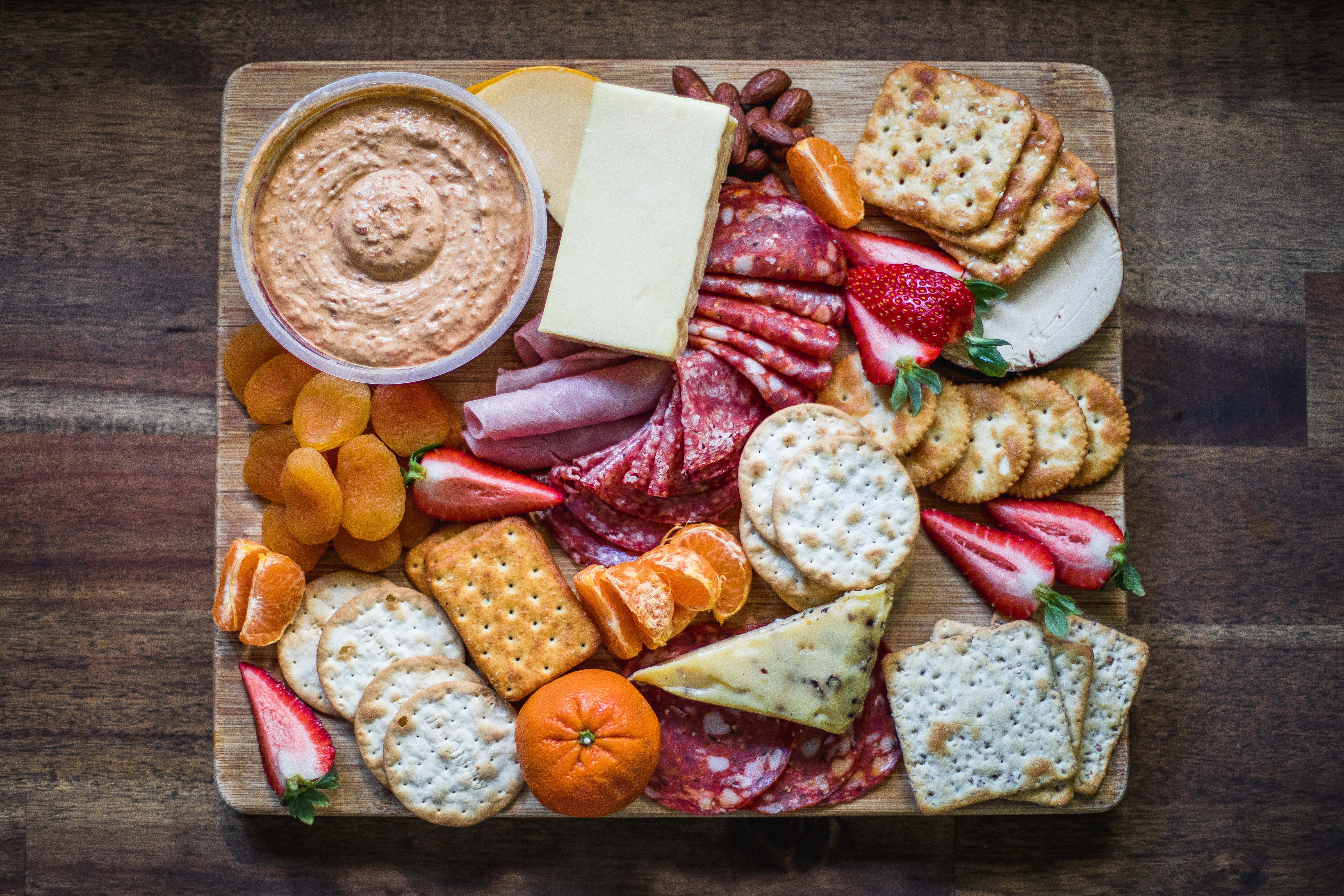 Cheese 桌布 壁紙 — 一個質樸的木板上擺滿了各式芝士、肉類、餅乾、草莓和橙瓣，構成色彩繽紛的熟食拼盤。