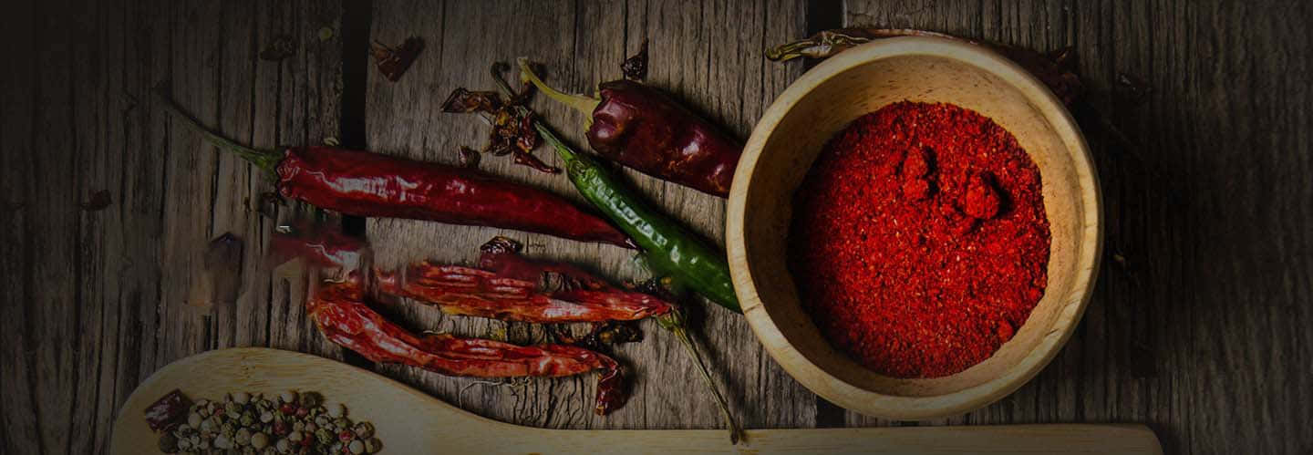 Red Chili Powder 桌布 壁紙 — 一個質樸的木碗裝滿了鮮紅色的辣椒粉，旁邊放著乾紅辣椒和青辣椒，放在經風化的木質表面上。