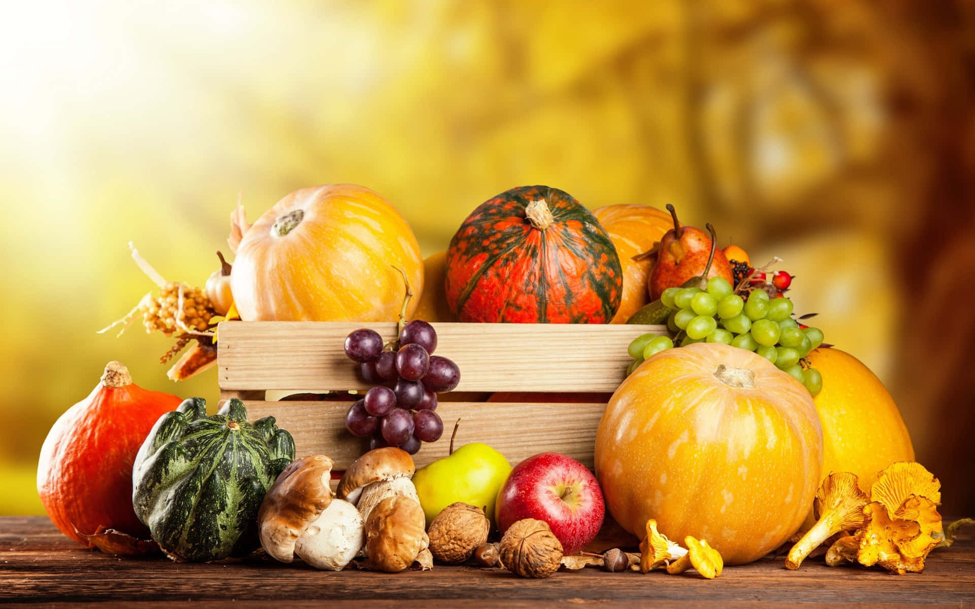 Autumn Food 桌布 壁紙 — 一個質樸的木箱，裝滿了色彩繽紛的秋季收穫物，包括南瓜、葡萄、蘋果和蘑菇，背景是溫暖的金色。