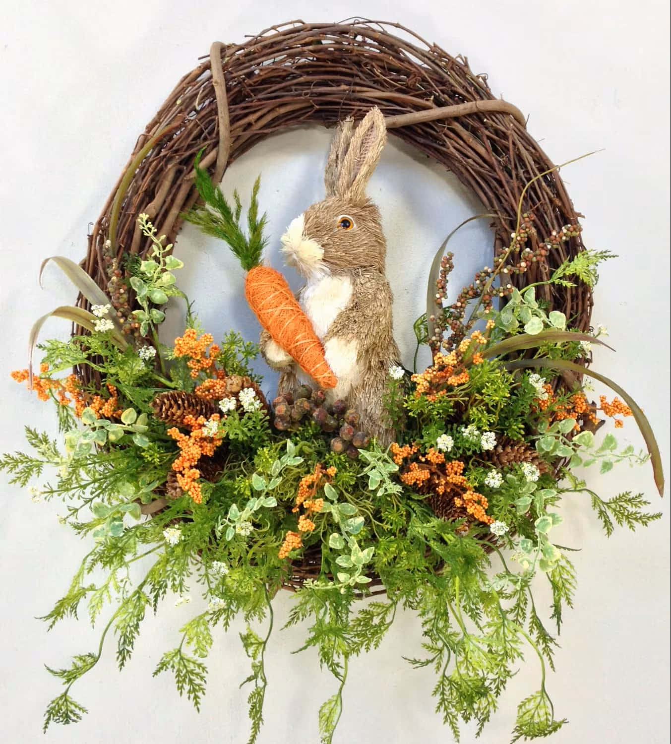 Spring Wreaths 桌布 壁紙 — 一個質樸的編織花環，飾有一隻毛絨兔子拿著胡蘿蔔，周圍環繞著綠色植物和橙色漿果。