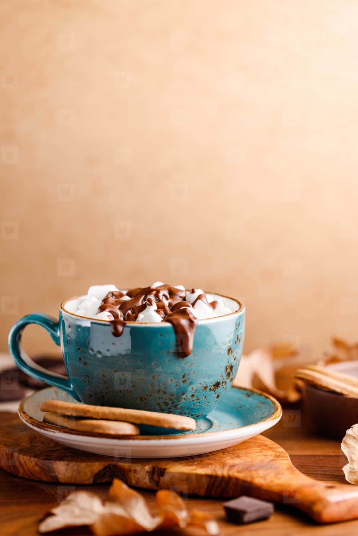 Hot Chocolate 桌布 壁紙 — 一個質樸的藍色陶瓷杯裝滿熱朱古力，上面加上忌廉和朱古力醬，放在木板上，周圍有秋葉和餅乾。