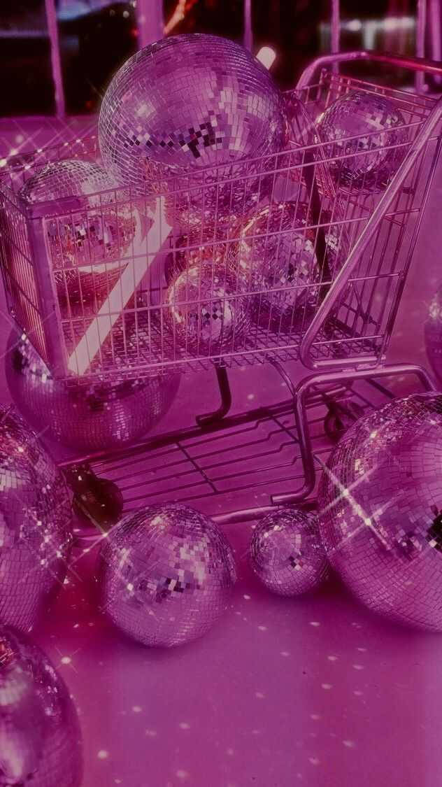 Sparkle 桌布 壁紙 — 一個購物車在充滿活力的粉紅光芒下，裝滿了閃閃發光的紫色迪斯科球。