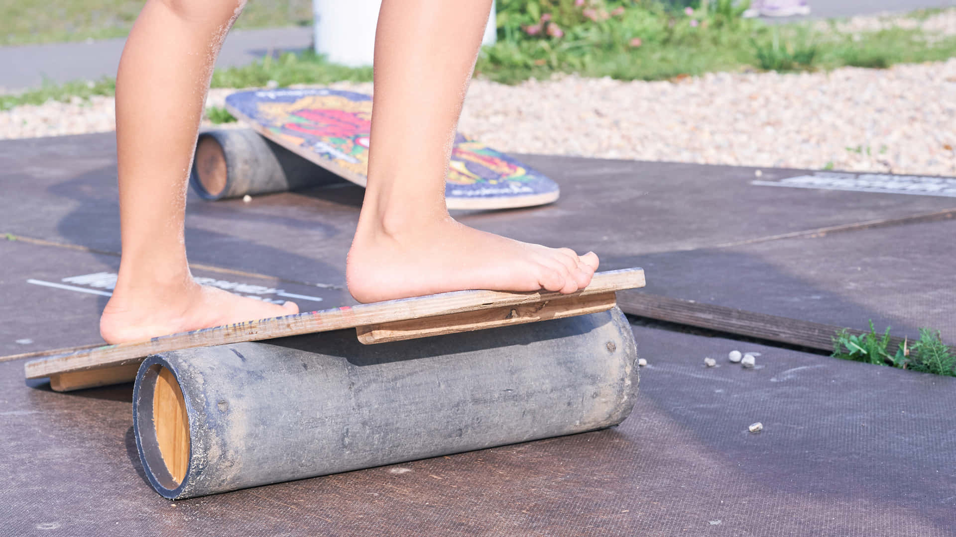 Outdoor Activities 桌布 壁紙 — 一個赤腳的人平衡喺一塊放喺風化嘅木頭上面嘅木板上，地下係一塊深色嘅墊，喺戶外。