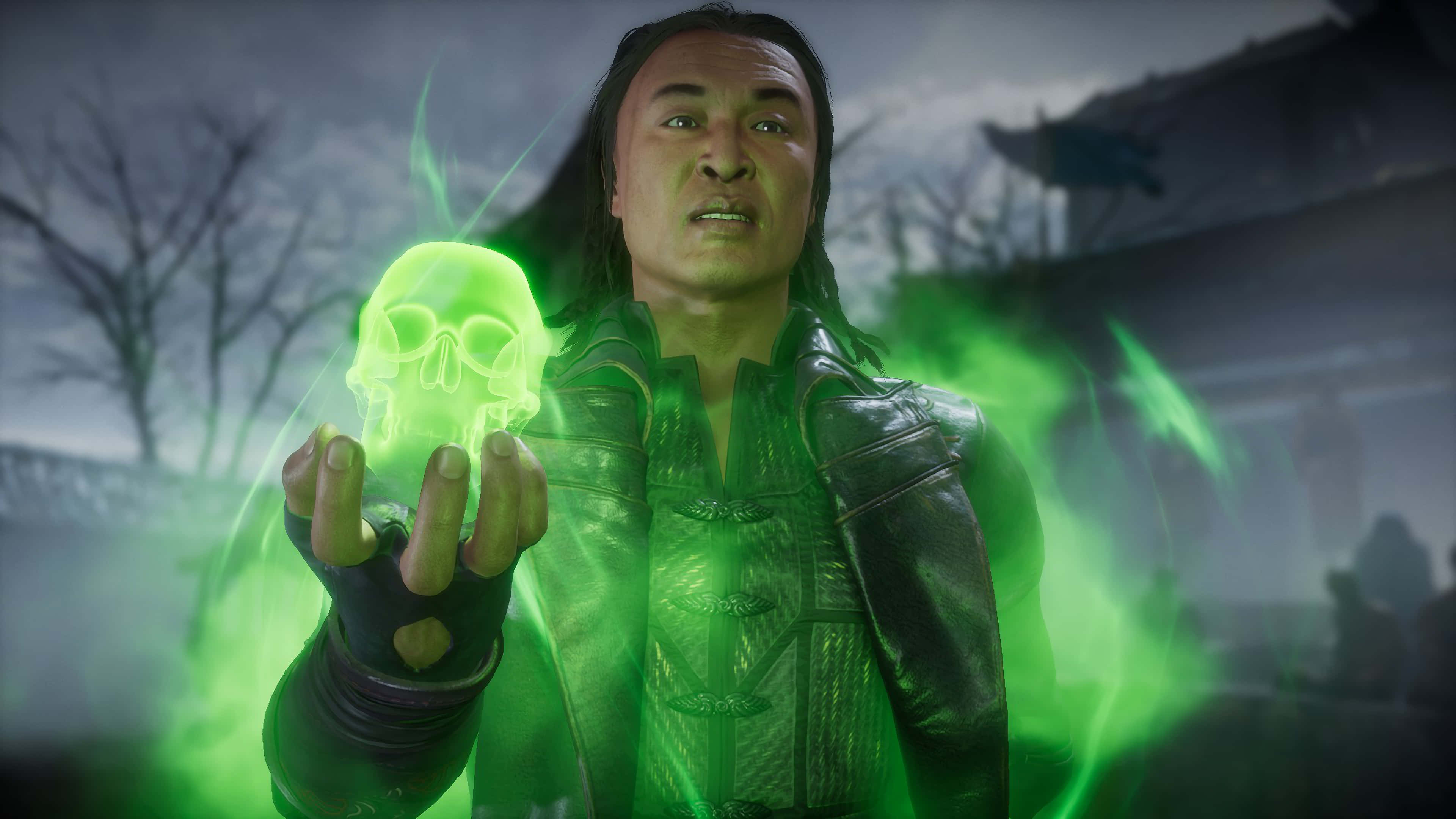Mortal Kombat Shang Tsung 桌布 壁紙 — 一個身穿暗色盔甲的男人手持一個發光的綠色頭骨，詭異的綠色能量在霧氣瀰漫的墓地中圍繞他旋轉。