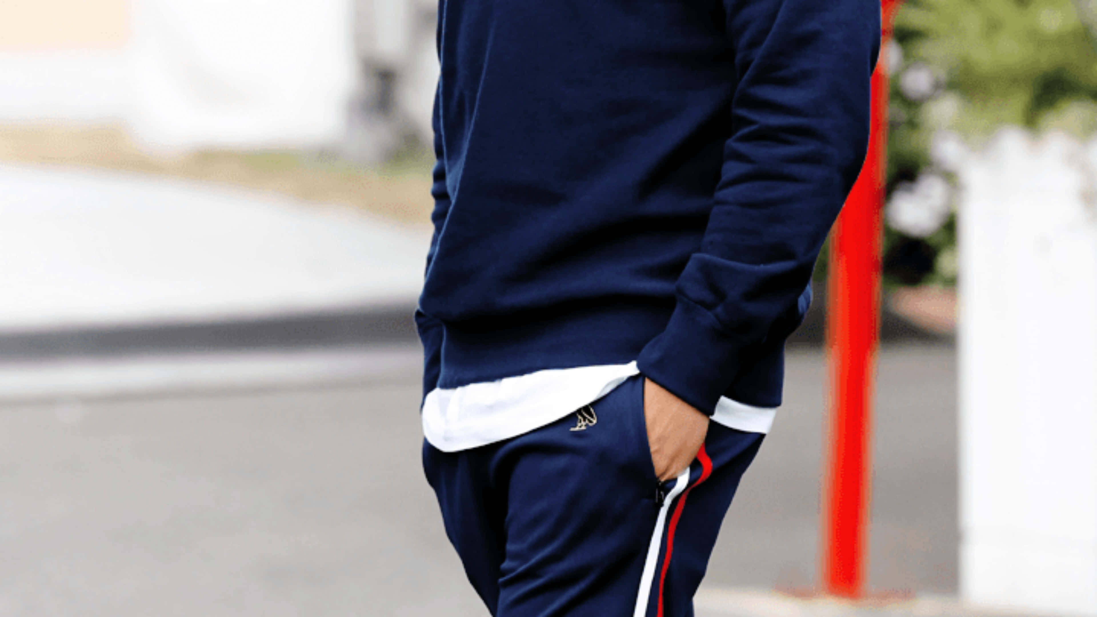 Drake 桌布 壁紙 — 一個身穿海軍藍白邊運動服的人，單手插袋，隨意地站在街上。