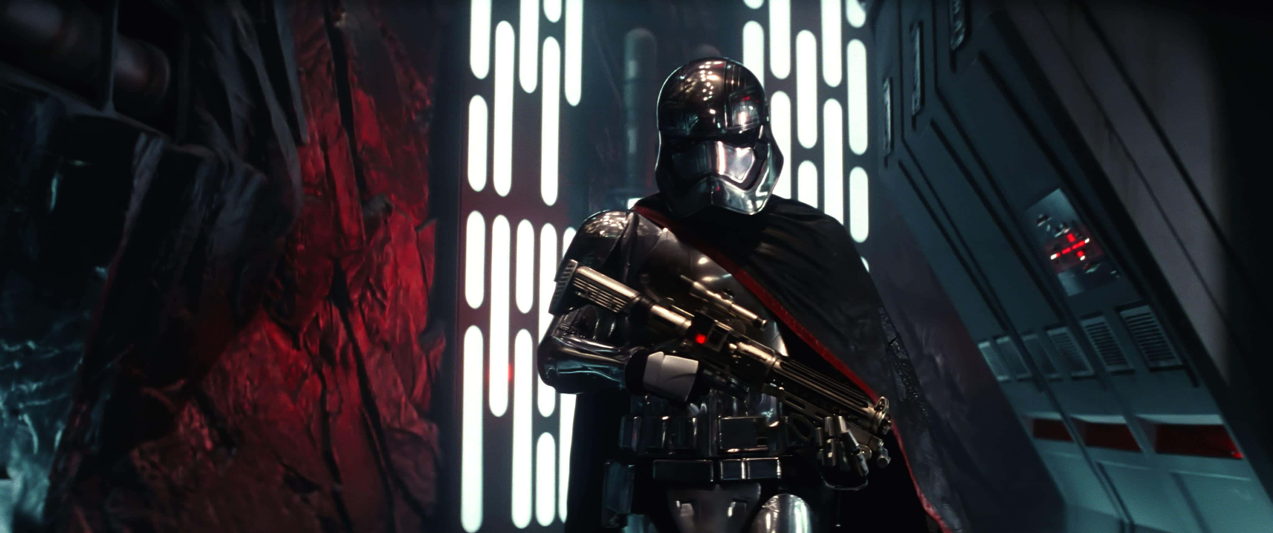 Captain Phasma 桌布 壁紙 — 一個身穿紅色斗篷的威嚇裝甲士兵站在一個由垂直發光面板照亮的昏暗未來主義走廊中。