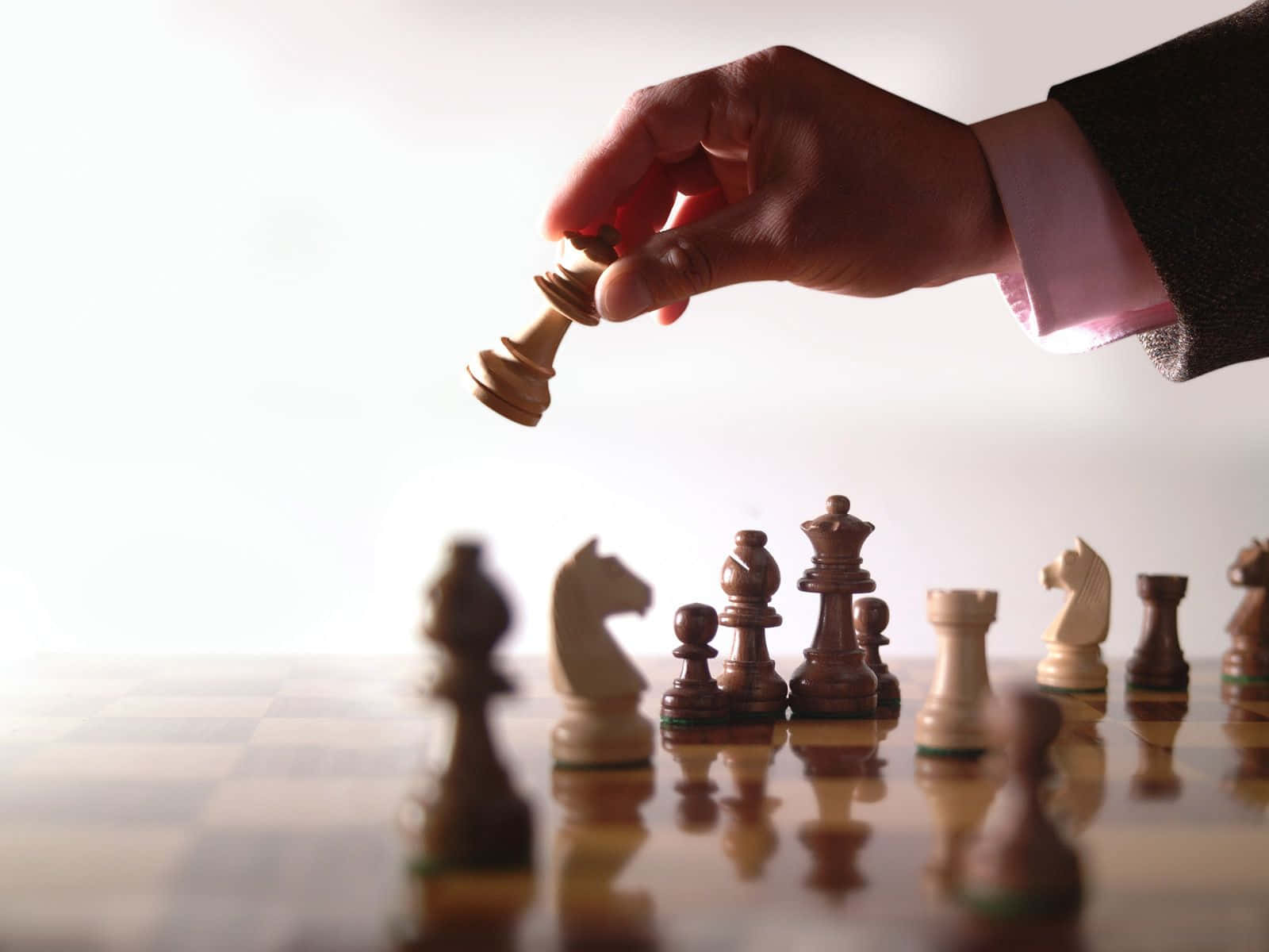 一個身穿西裝的男人正在將一枚棋子放到棋盤上 壁紙