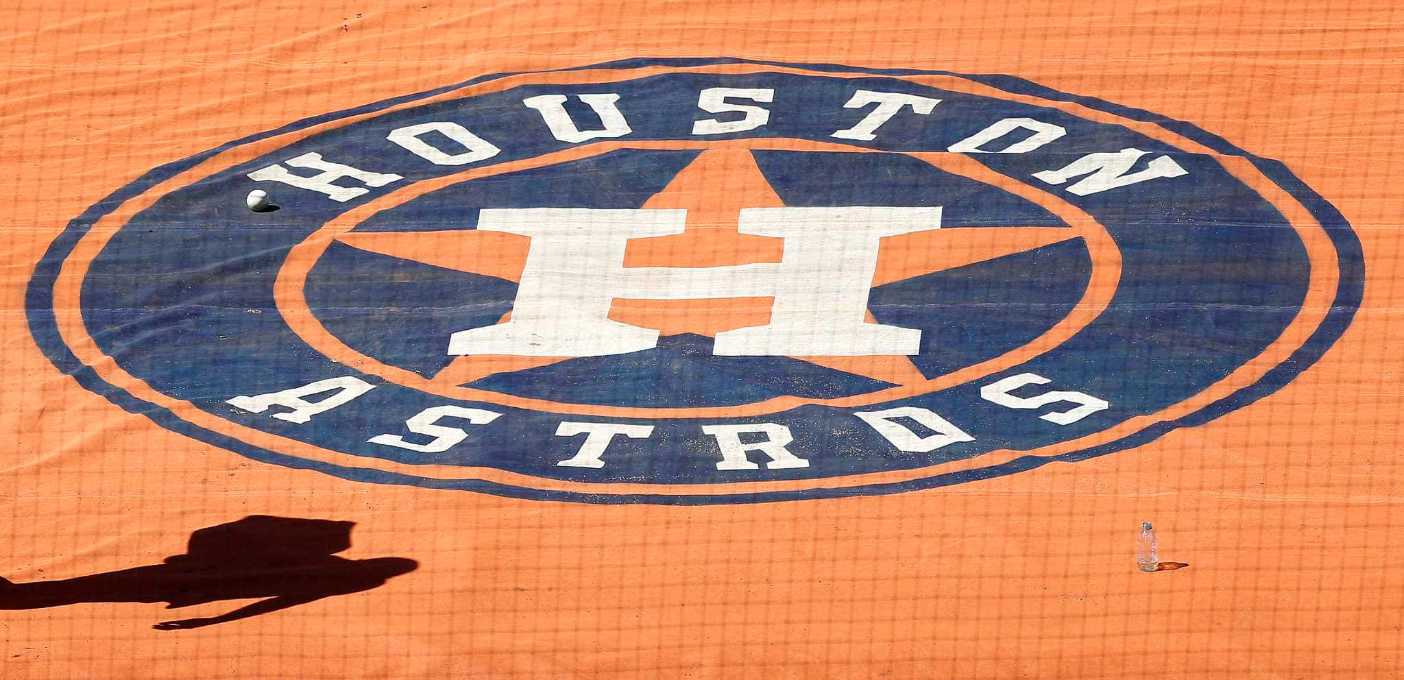 Astros 桌布 壁紙 — 一個近距離拍攝的侯斯頓太空人標誌，繪在橙色網狀表面上，並有人的影子投射在上面。