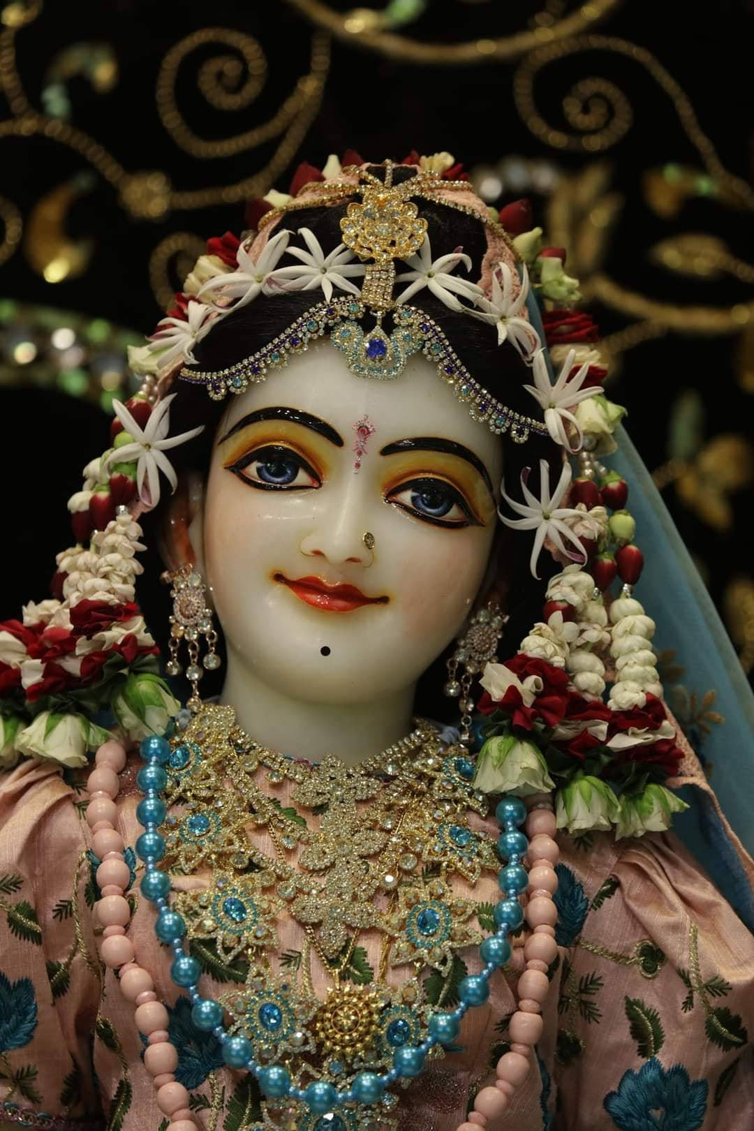 Indian 桌布 壁紙 — 一個近距離拍攝的美麗裝飾印度教神像，帶有複雜的珠寶和花環，背景是深色華麗的。