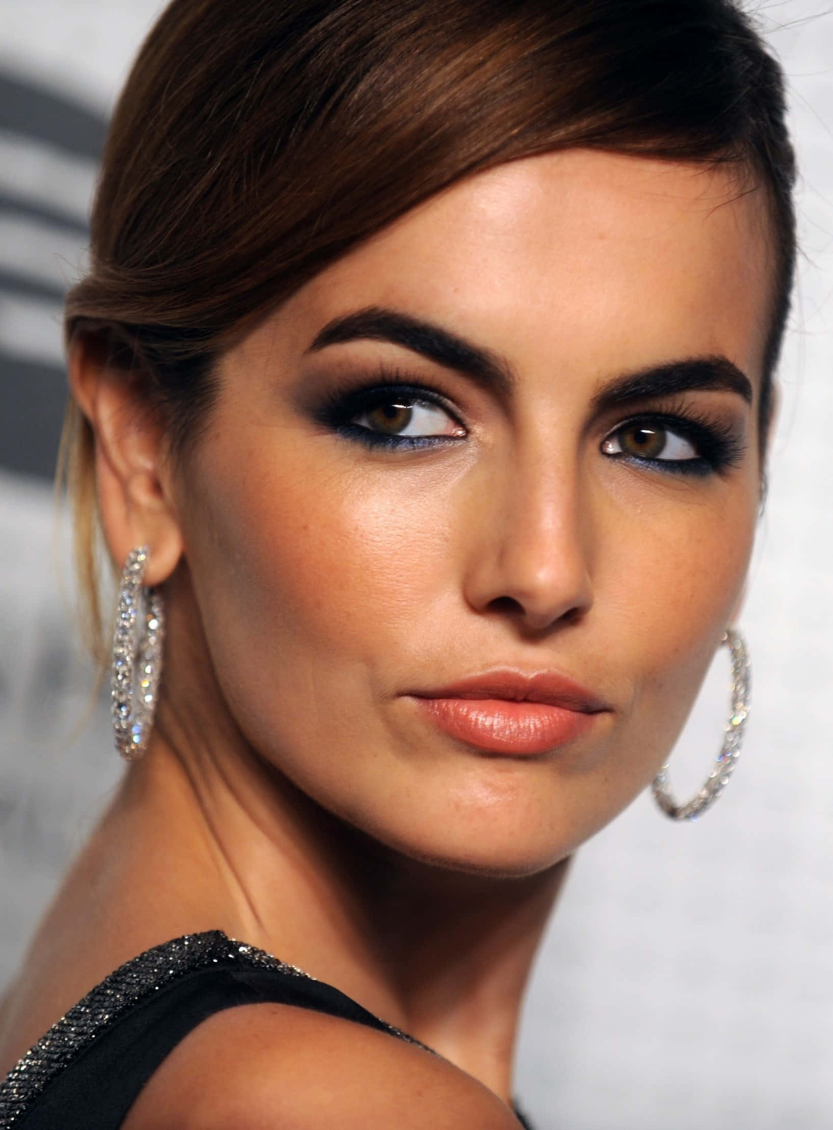Camilla Belle 桌布 壁紙 — 一個迷人嘅特寫鏡頭，影住一個化咗大膽妝容、戴住閃亮圈圈耳環嘅女人，背景係模糊嘅。