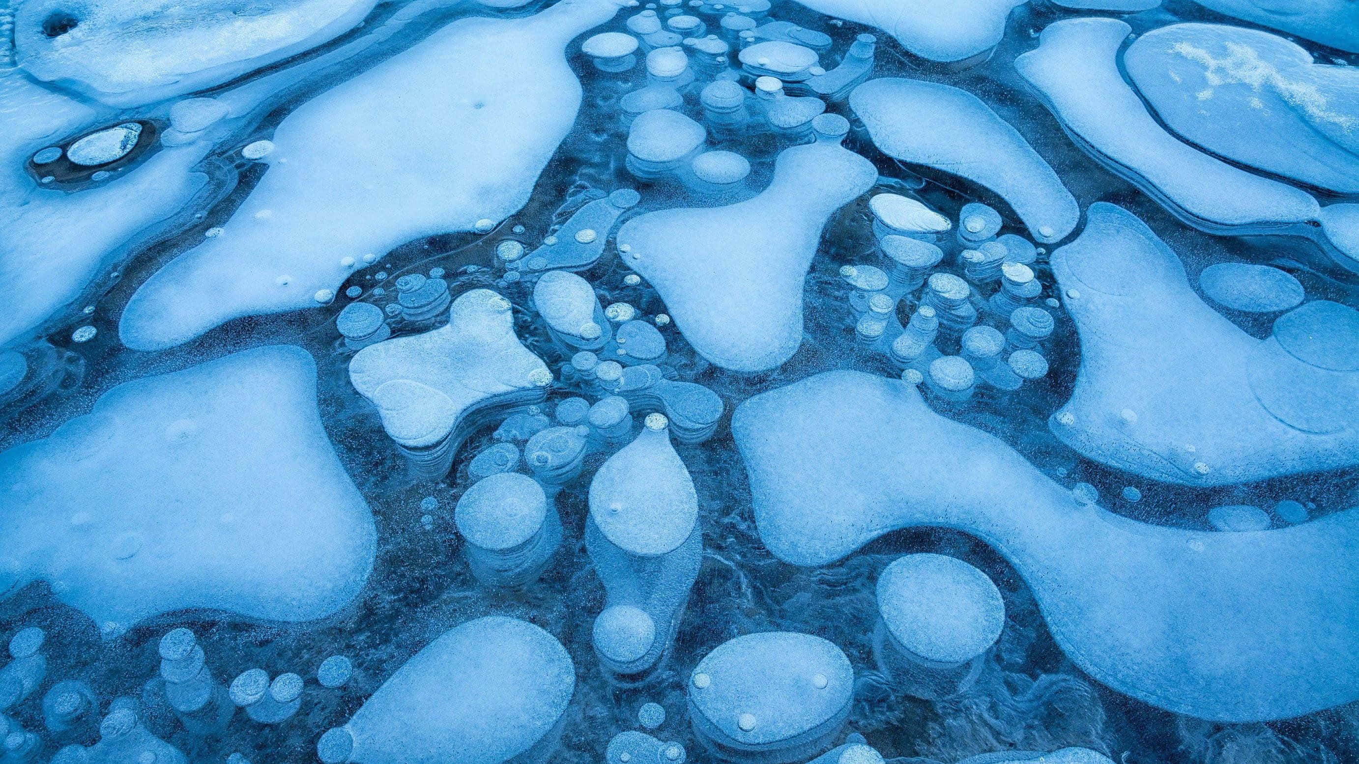 Frozen Lake 桌布 壁紙 — 一個迷人的特寫，冰凍的氣泡被困在半透明的藍色冰中，形成有機圖案。
