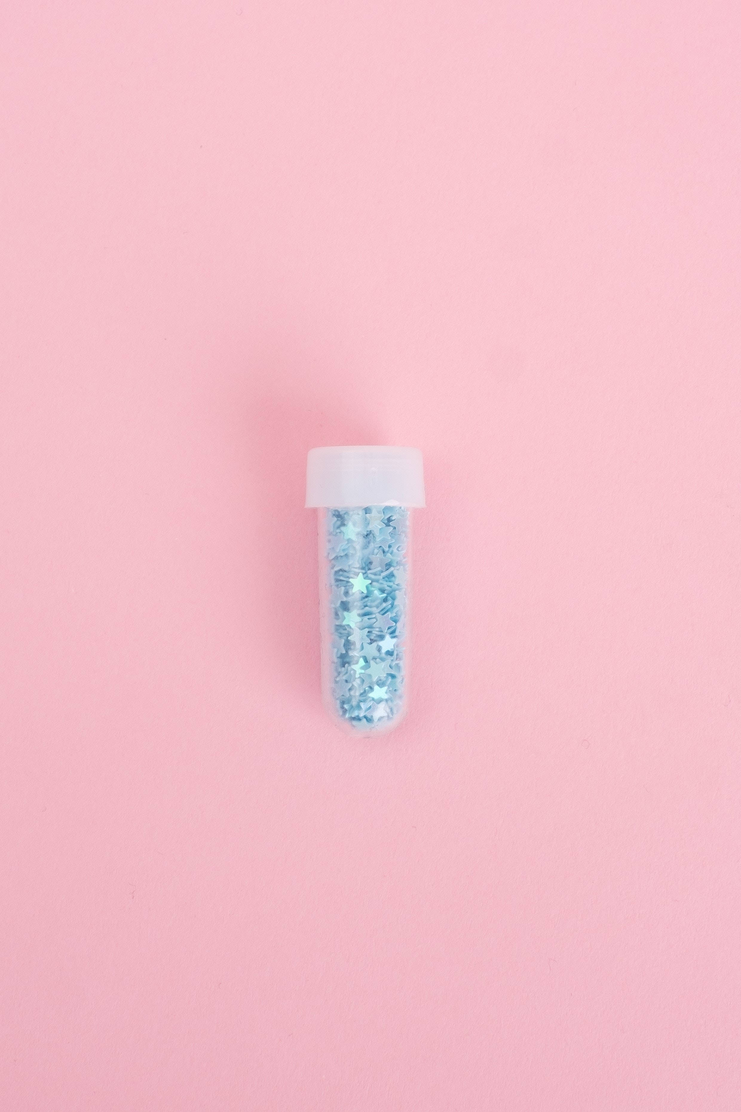 Pink And Blue 桌布 壁紙 — 一個透明塑膠管裝滿藍色閃粉，置於柔和粉紅色背景中央。
