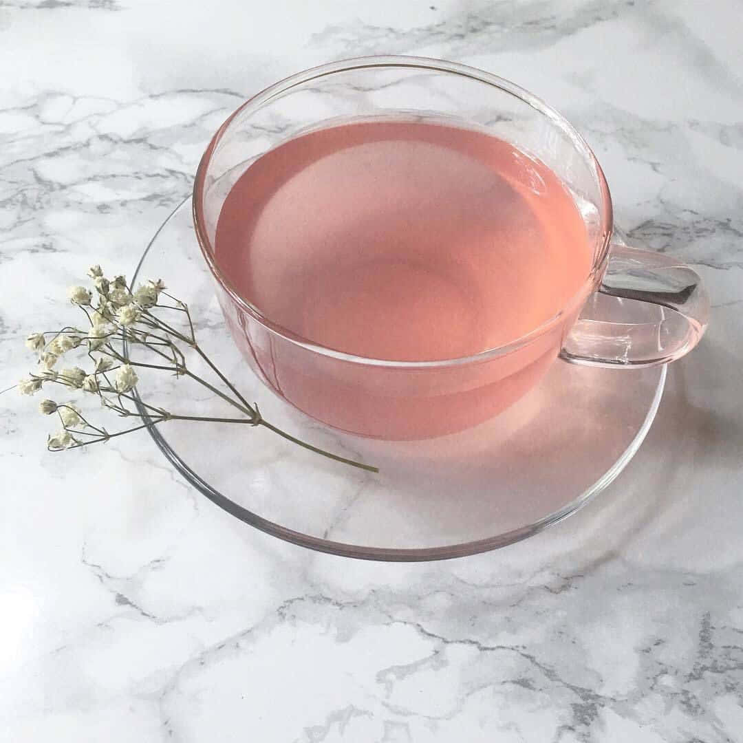 Pink Tea 桌布 壁紙 — 一個透明玻璃杯裝滿粉紅茶，放在大理石表面上，旁邊是精緻的乾燥滿天星花。