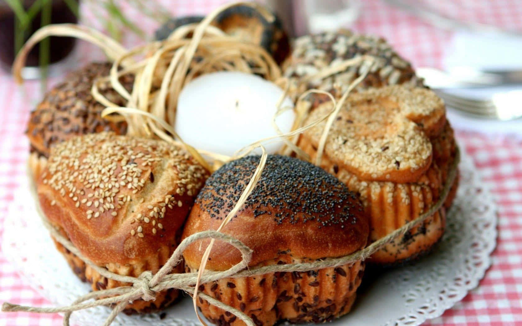 Bakery 桌布 壁紙 — 一個鄉村風格的籃子，裡面裝著各種用麻繩捆綁的種子麵包卷，上面放著一個白蛋，放在紅色格子桌布上。