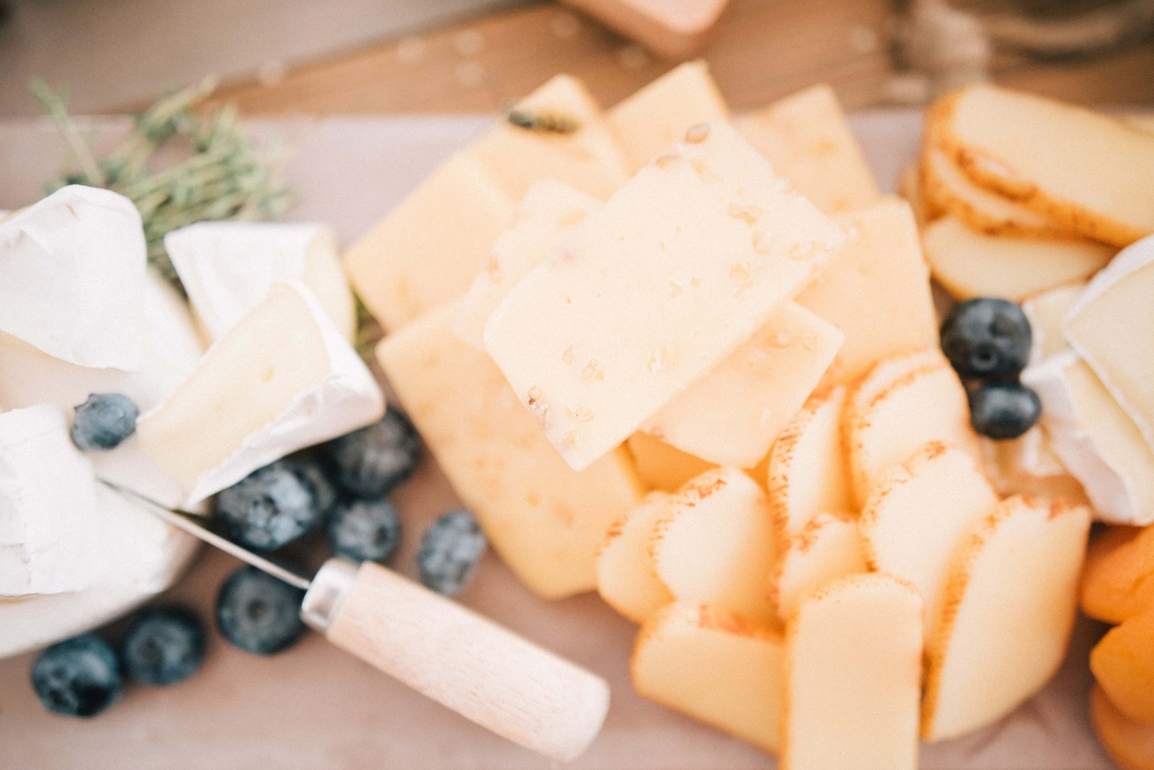 Cheese 桌布 壁紙 — 一個鄉村風格的芝士拼盤，包含各種奶油芝士和硬芝士，並以新鮮藍莓和香草點綴。