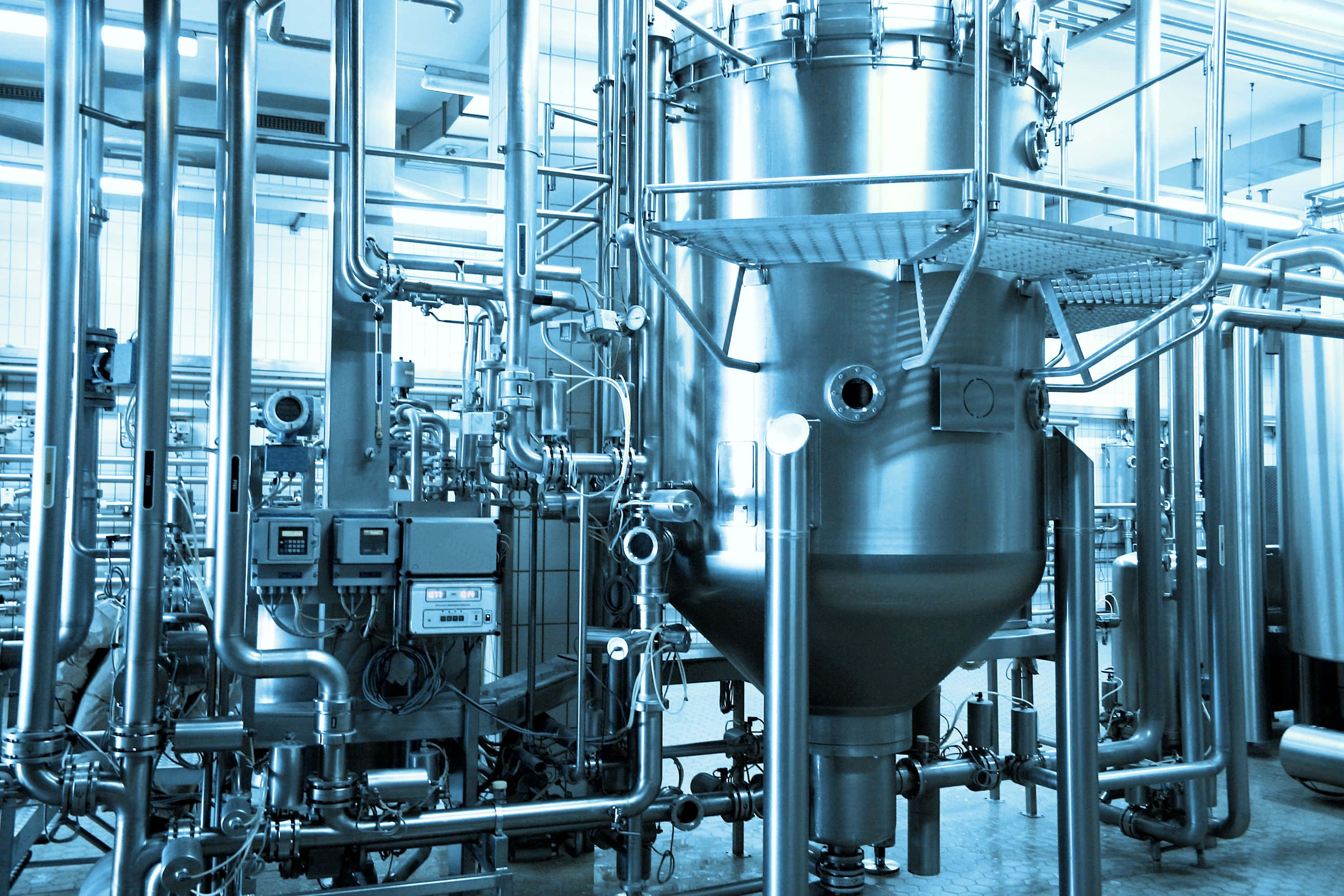 Manufacturing 桌布 壁紙 — 一個酷炫的藍色調工業啤酒廠內部，配有不銹鋼大桶和複雜的管道系統。