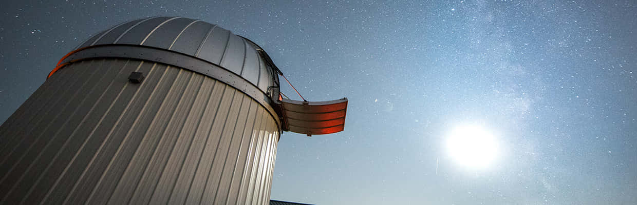 Observatory 桌布 壁紙 — 一個金屬天文台圓頂矗立在繁星點點的夜空下，銀河和明亮的月亮在上方閃耀。