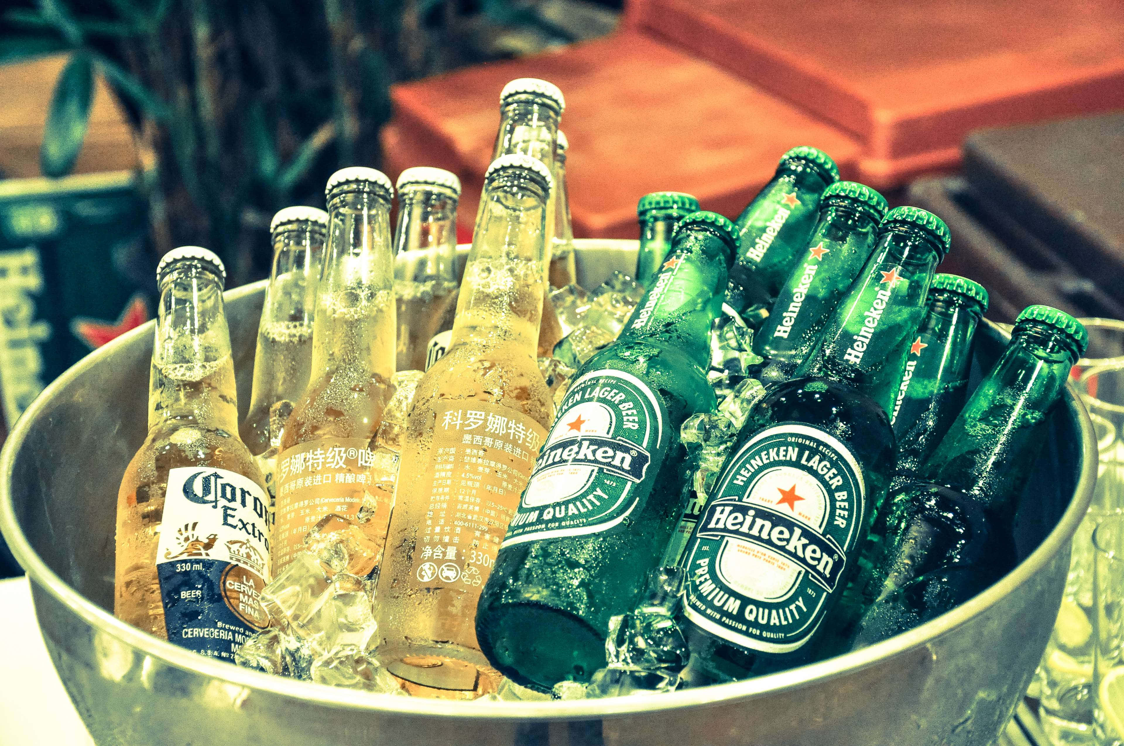 Heineken 桌布 壁紙 — 一個金屬桶裝滿冰塊和各種冰凍啤酒瓶，包括喜力和科羅娜特級啤酒。