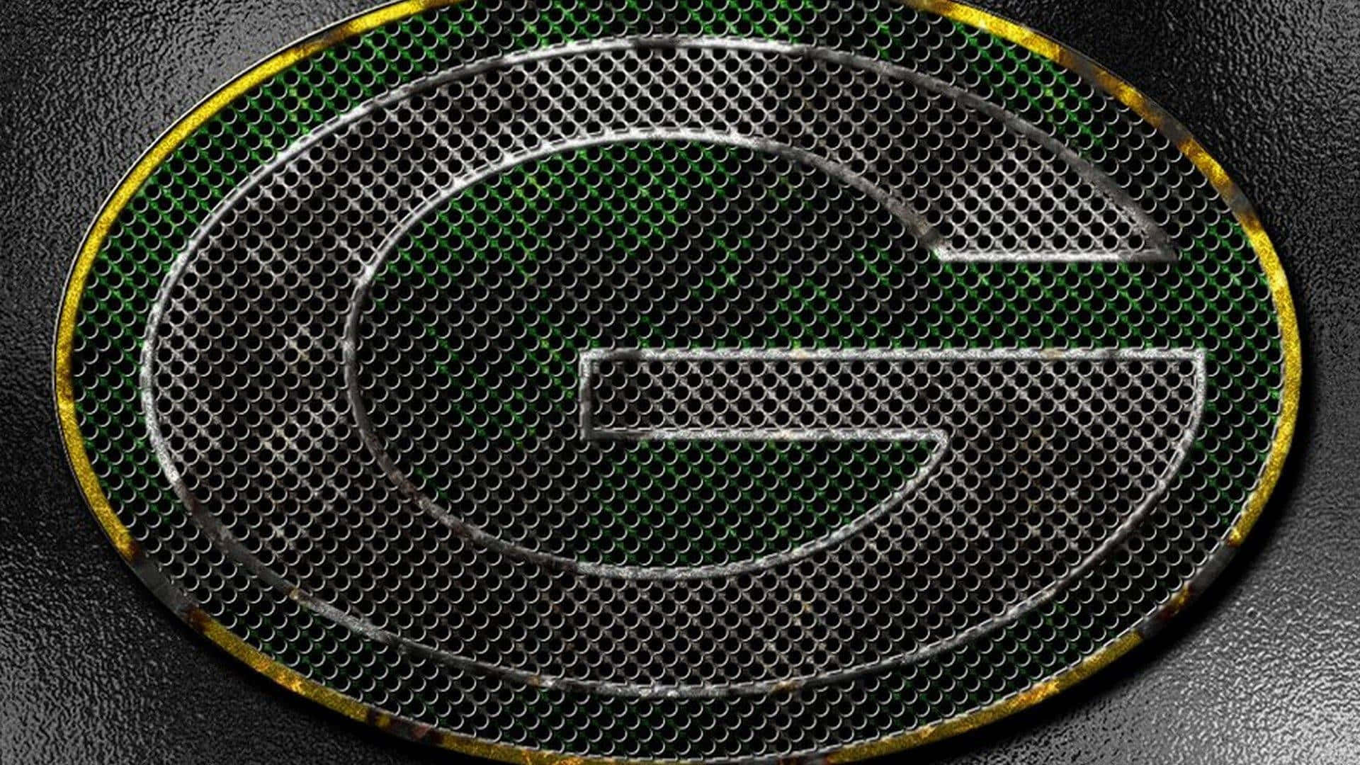 Packers 桌布 壁紙 — 一個金屬綠色和金色的 'G' 標誌蝕刻在帶有紋理深色背景的穿孔金屬格柵上。