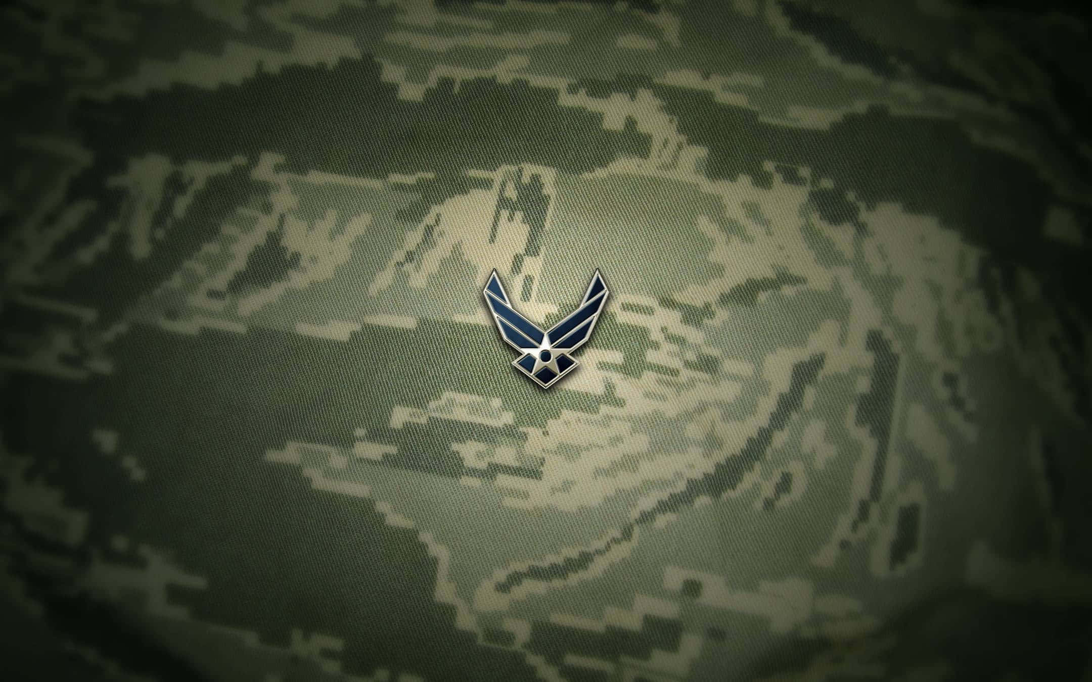 空軍 桌布 壁紙 — 一個金屬製的美國空軍翼章在數碼迷彩布料背景中央閃耀。