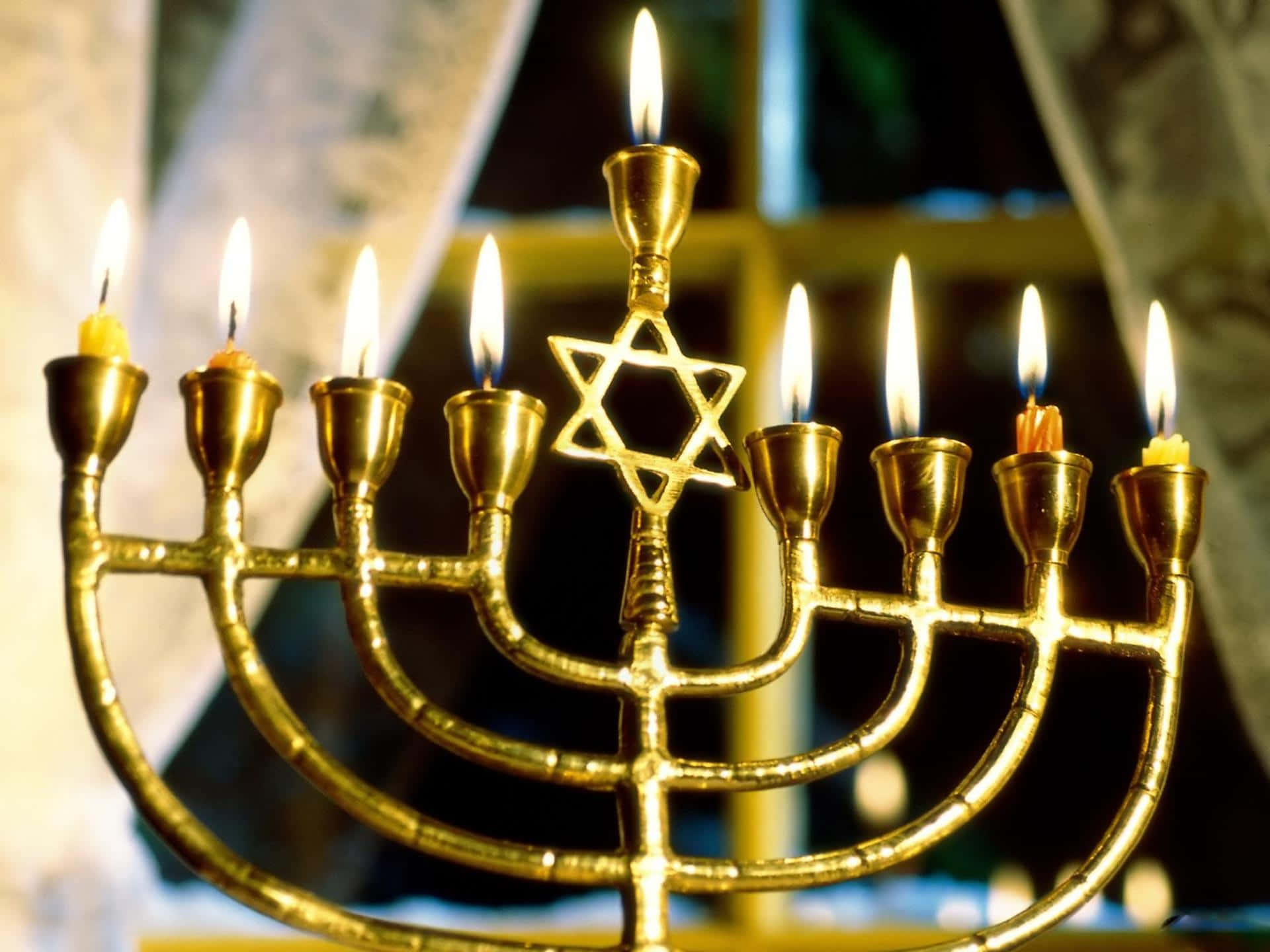 Hanukkah 桌布 壁紙 — 一個金色的九枝燭台，點燃九根蠟燭，中央有大衛之星，在黑暗背景中溫暖地發光。