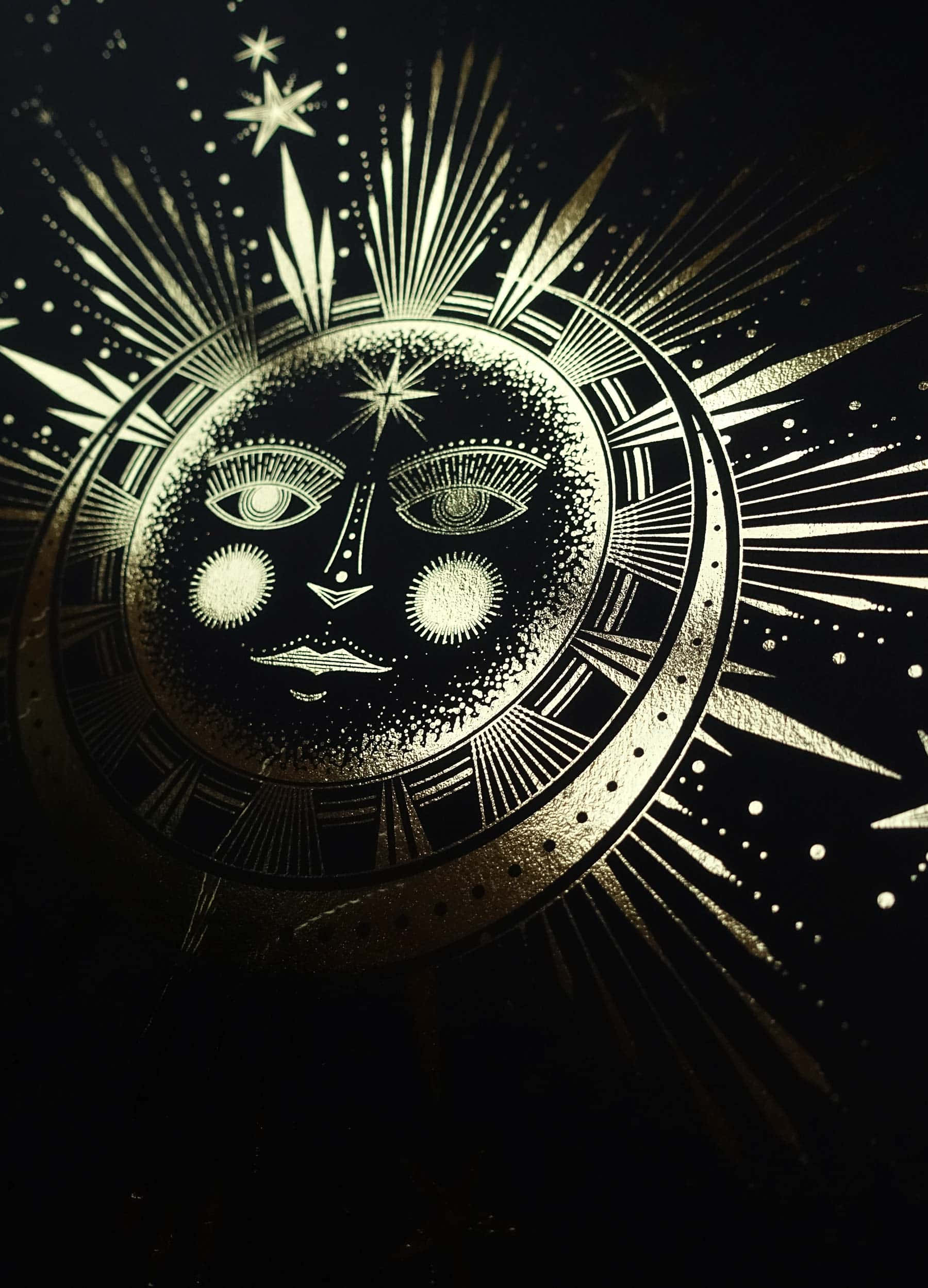 太陽與月亮 桌布 壁紙 — 一個金色的天體面孔，帶有複雜的眼睛和光線，在黑暗的星空背景下散發光芒。