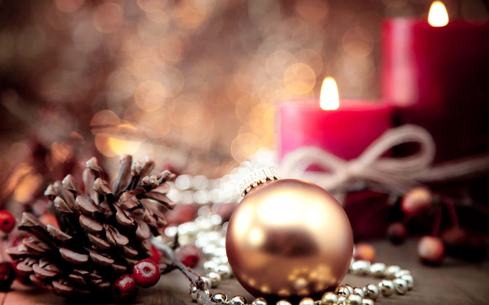 Rustic Christmas 桌布 壁紙 — 一個金色聖誕裝飾品放在松果和紅莓旁邊，背景有柔和散景的發光蠟燭。