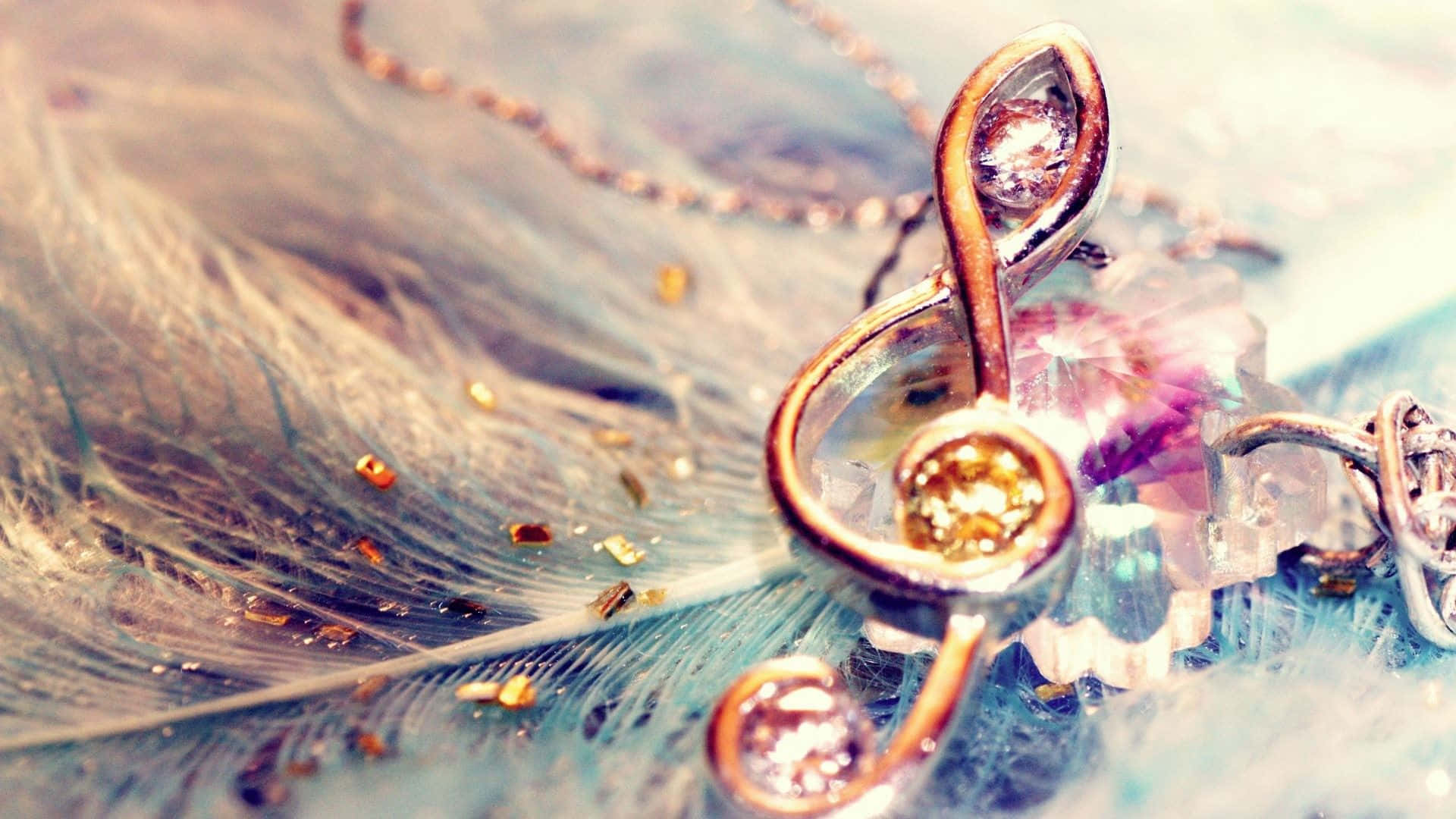 Cute Music 桌布 壁紙 — 一個金色高音譜號吊墜，鑲有閃爍寶石，放在一條飾有閃爍金片的柔軟藍色羽毛上。