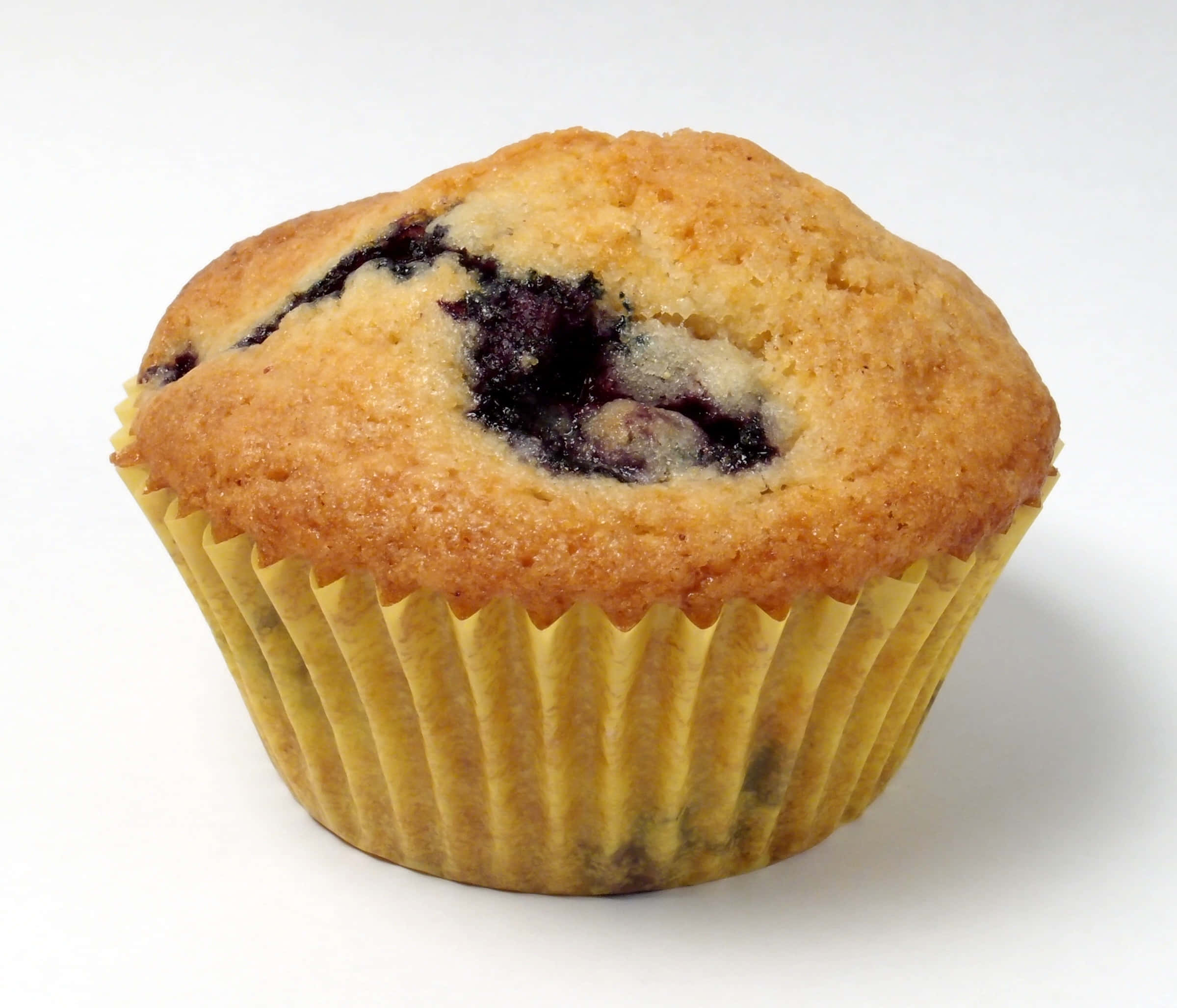 Blueberry Muffins 桌布 壁紙 — 一個金黃色的藍莓鬆餅，頂部爆出多汁的深色莓果，放在黃色波浪紋紙杯裡，襯著潔白的背景。